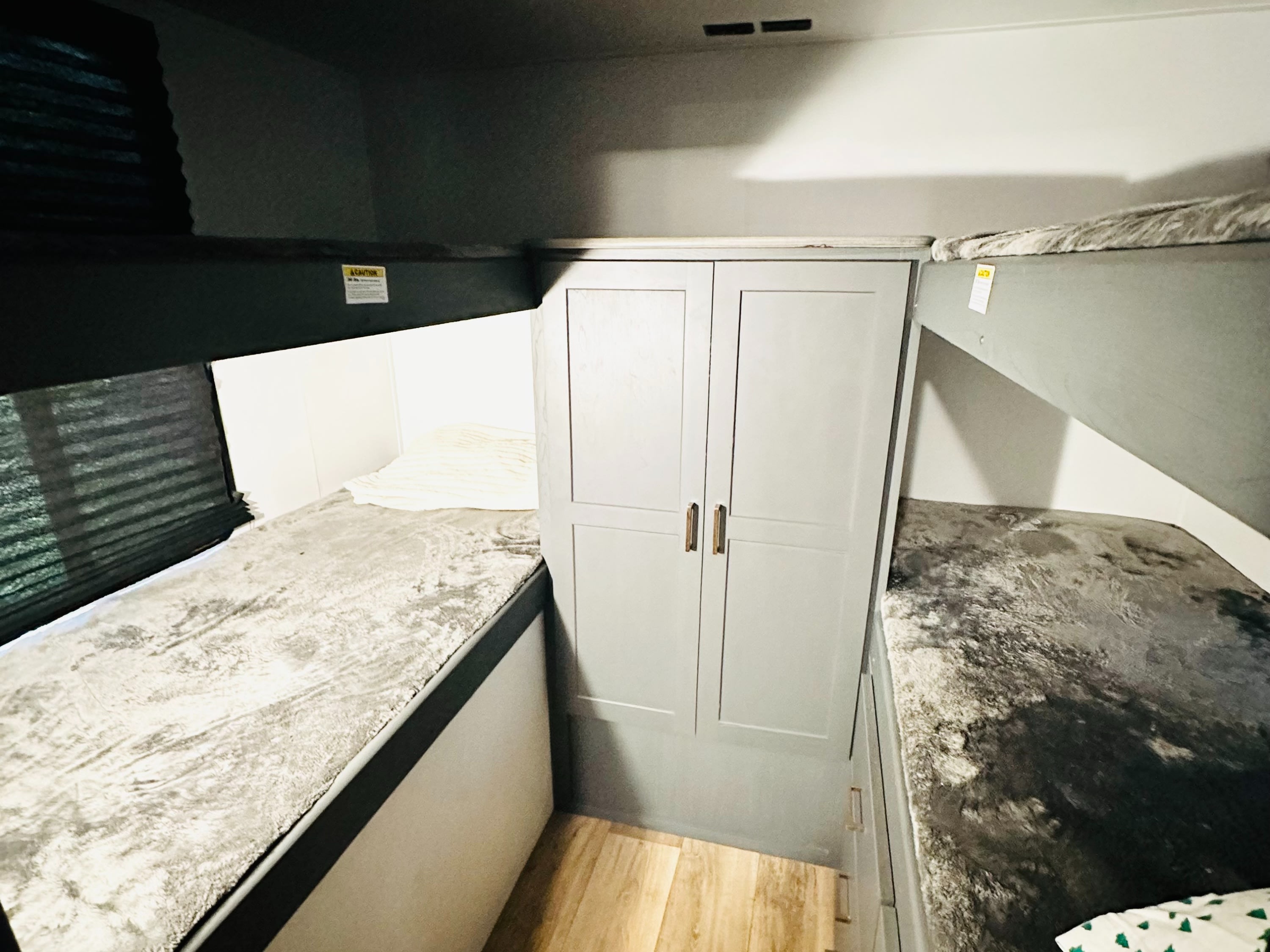 Inside an rv rental: gray bunk beds, central wardrobe, and wood flooring. A compact and functional sleeping space.. Keystone RV Bullet Crossfire 2024
