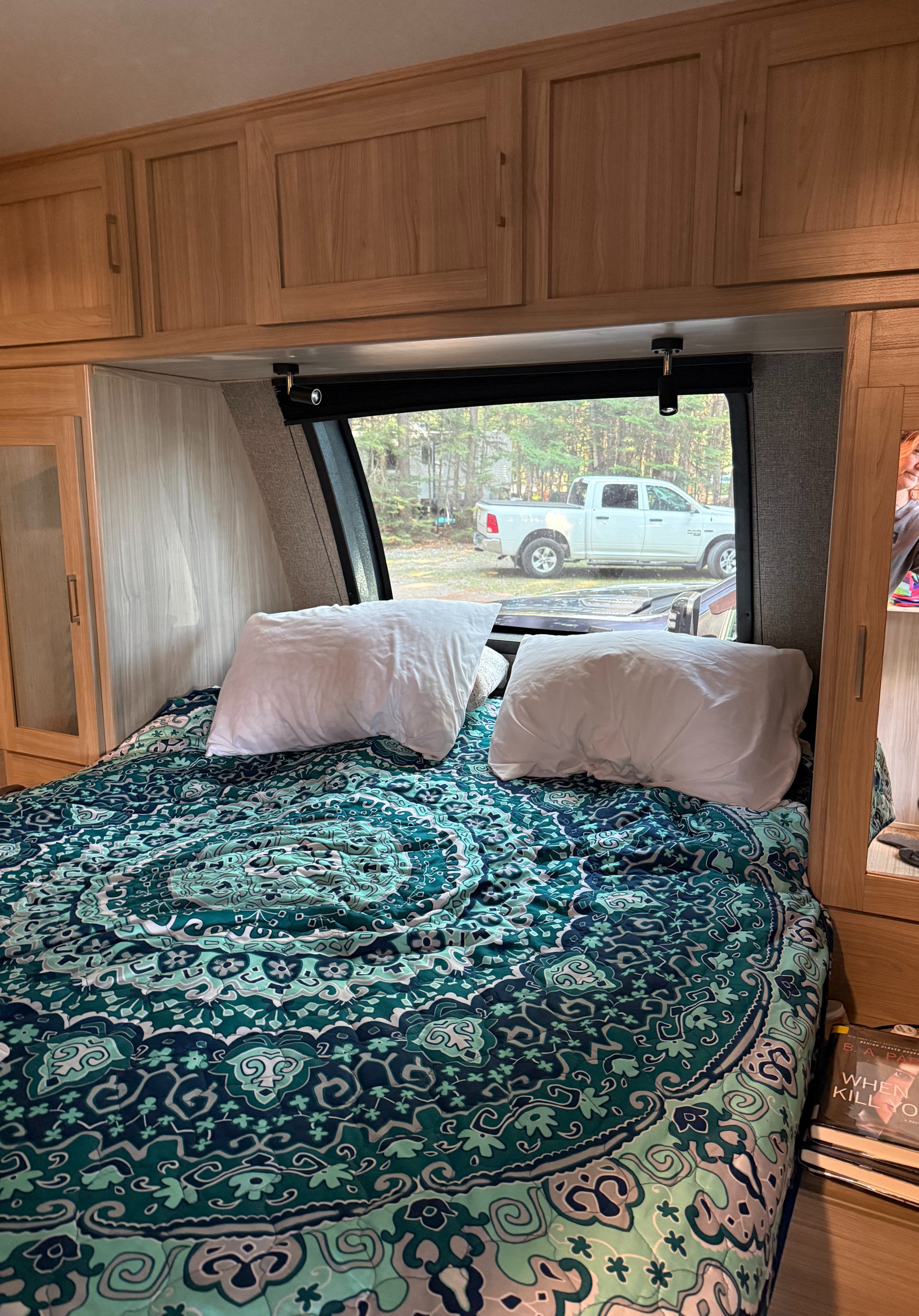 Cozy RV rental bedroom with patterned bed, overhead storage, and a scenic window view of nature.. Forest River Coachmen Freedom Express Ultra Lite 2020
