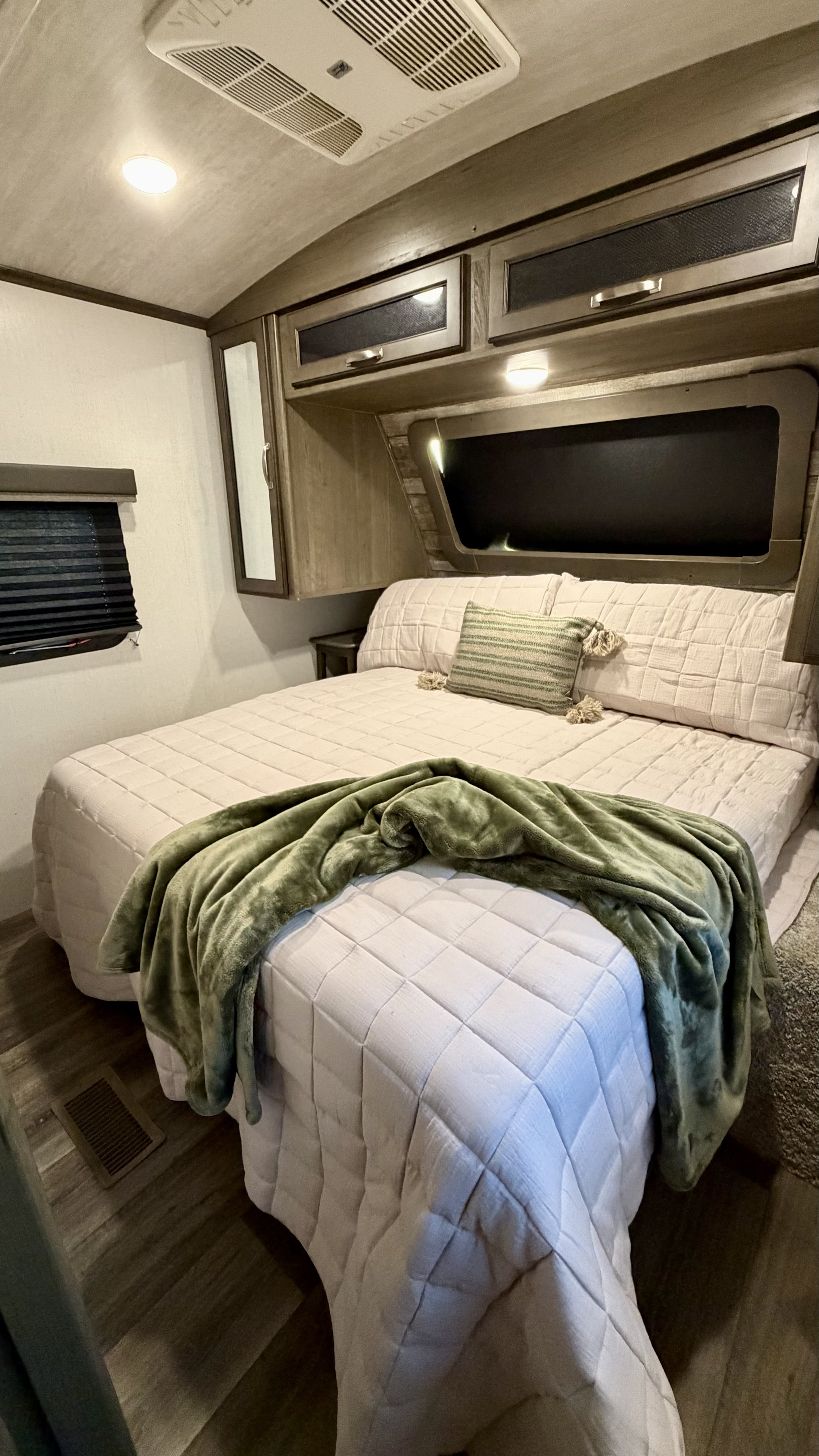 Cozy RV rental bedroom with a comfy bed, quilted bedding, and overhead storage. Perfect for your next adventure.. Keystone RV Cougar 2021