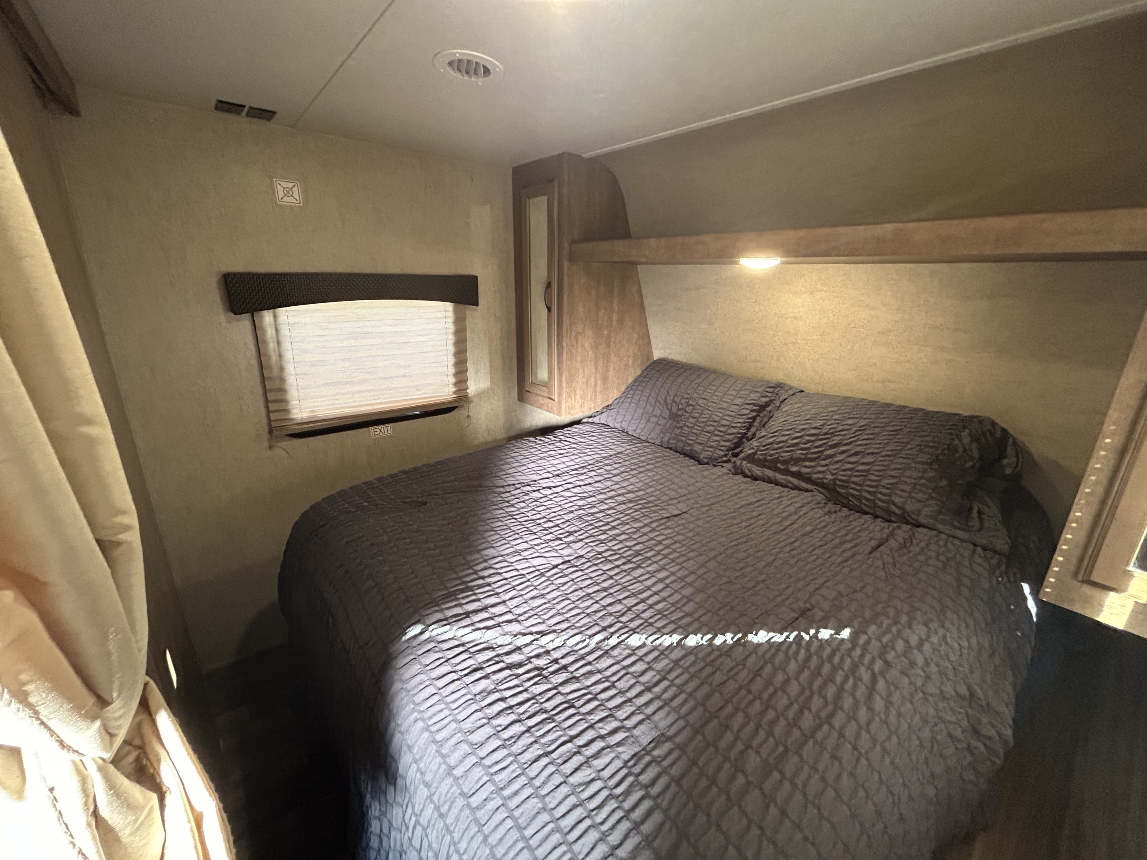 RV rental bedroom featuring a queen bed, window with blinds, overhead storage, and ceiling vents. Cozy and functional.. Starcraft Launch Ultra Lite 2017