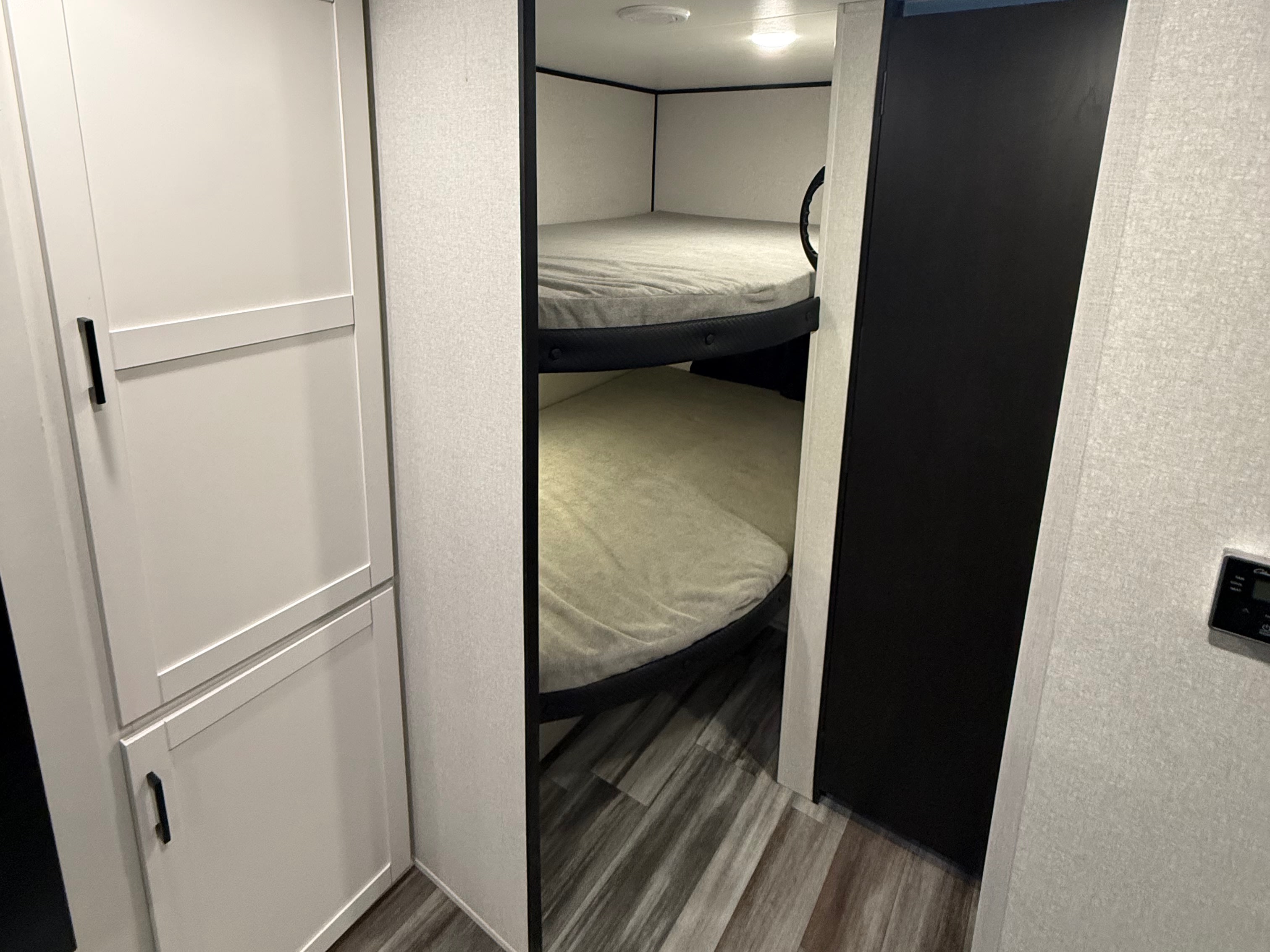 Inside an RV rental: clean bunk beds with light mattresses, sleek white cabinets, and wood-patterned flooring.. Jayco Jay Flight SLX 2026