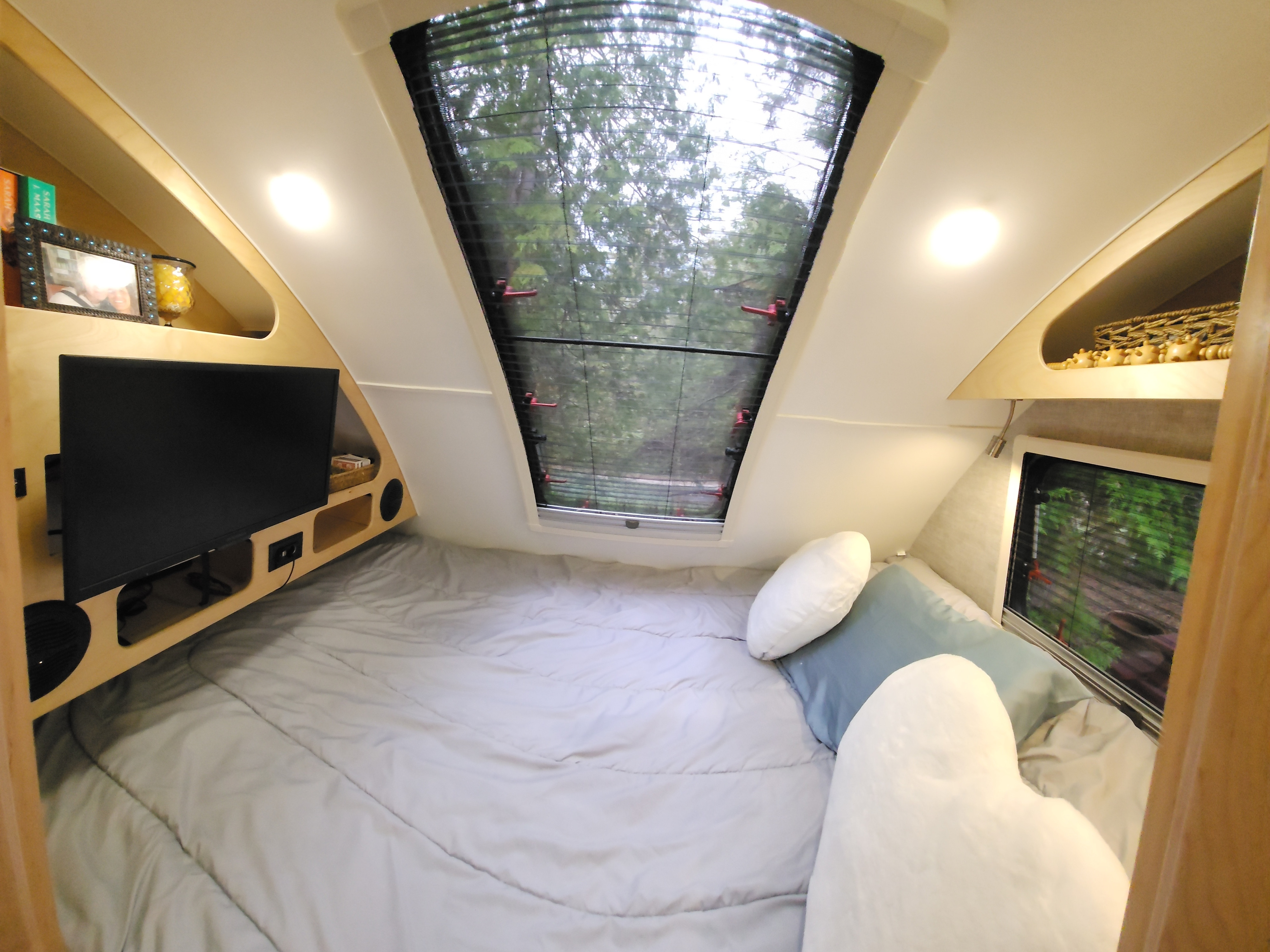 Cozy RV rental bedroom featuring a large bed, TV, overhead storage, and a beautiful skylight view of trees outside.. Xtreme Outdoors Xtreme Outdoors Trailer 2024