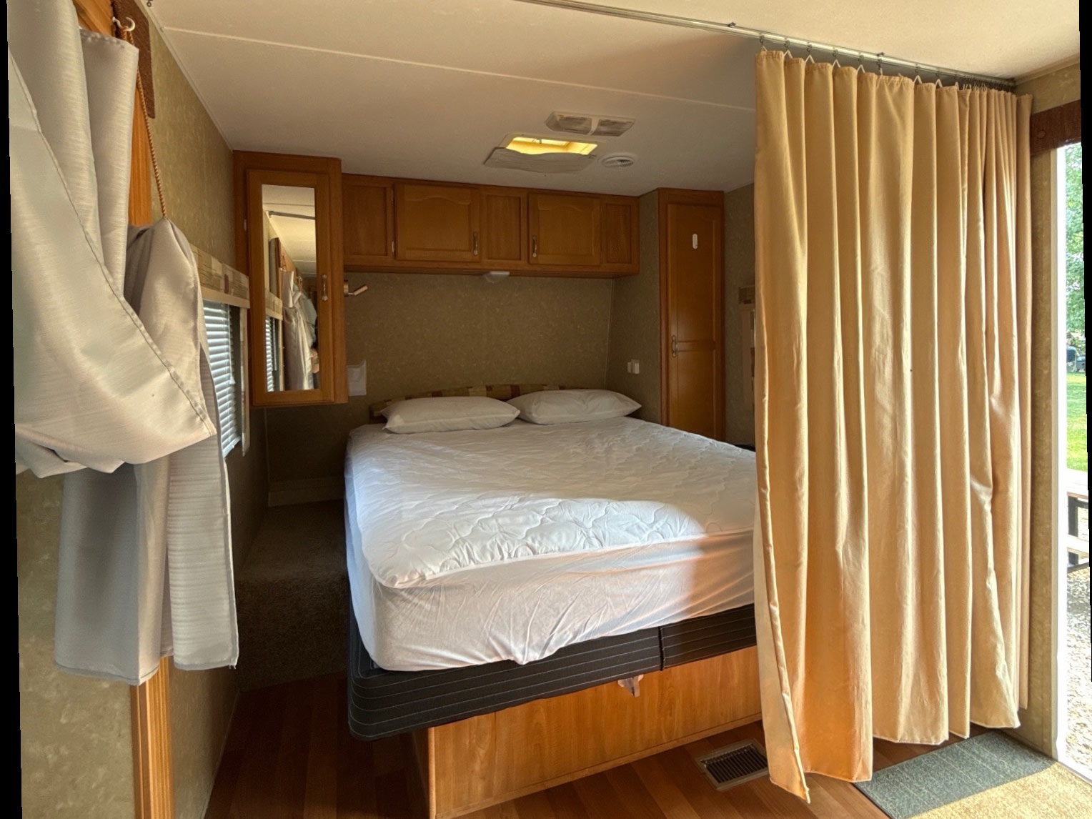Cozy RV rental bedroom with a comfortable bed, overhead cabinets, and a privacy curtain for a restful stay on your adventure.. Gulf Stream Conquest 2009