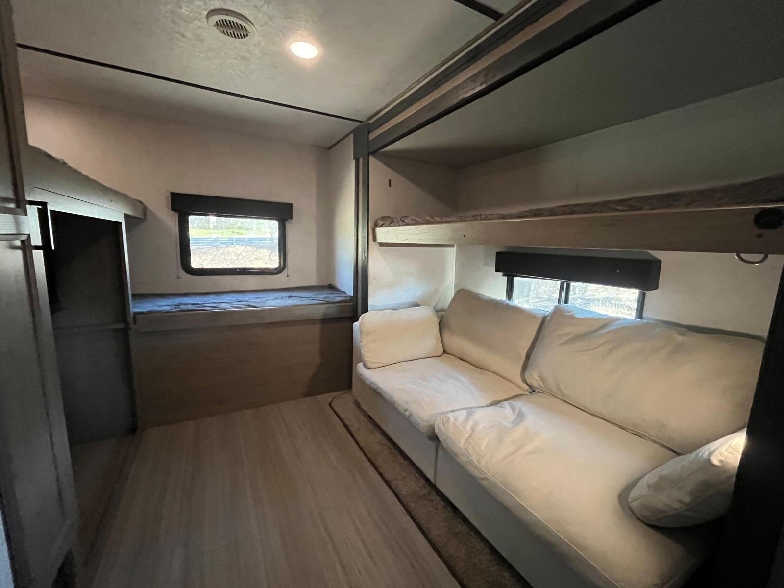 Spacious RV rental interior featuring bunk beds and a cozy white sofa, perfect for comfortable travel.. Keystone RV Hideout 2021