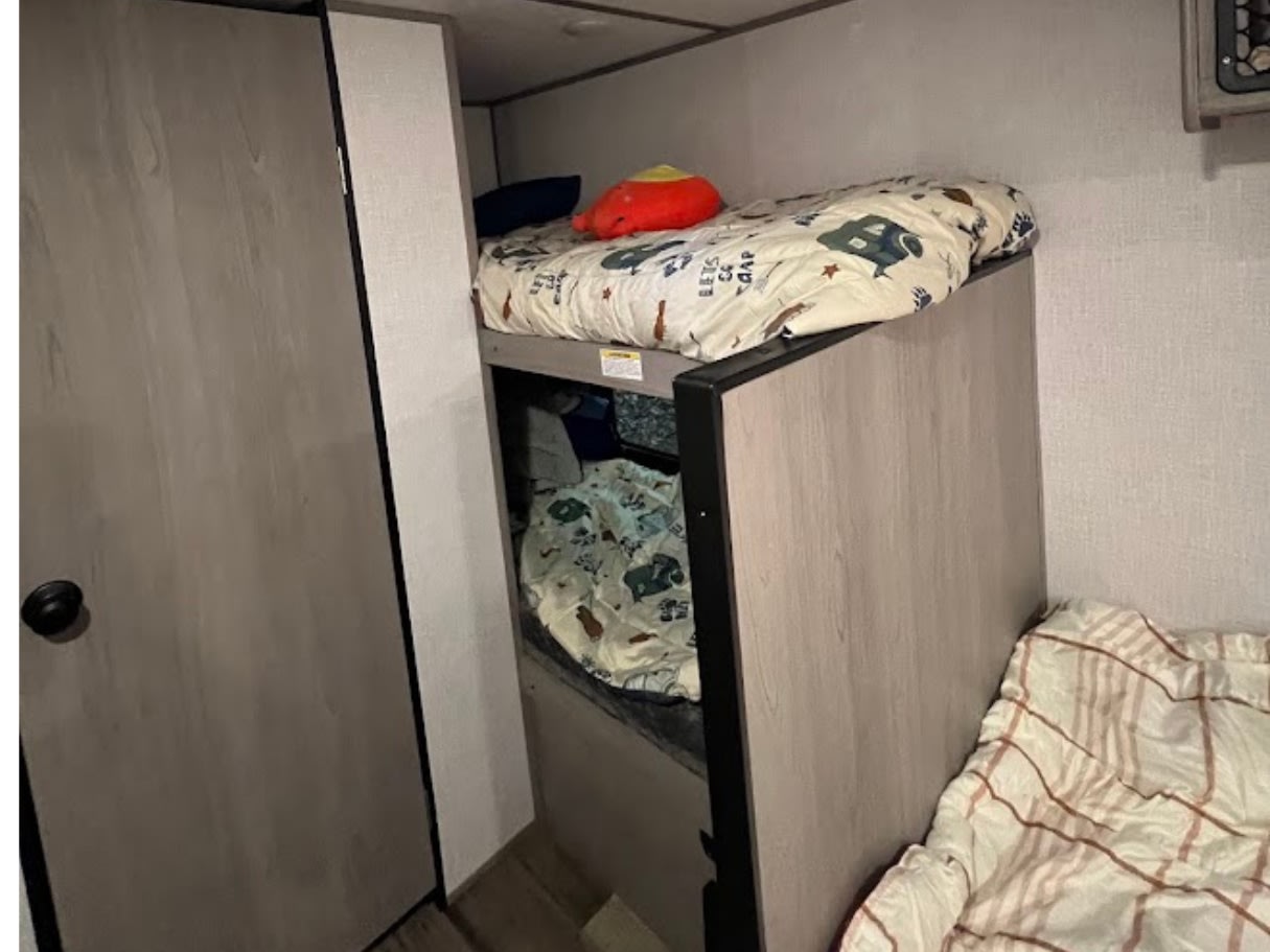 Inside an RV rental: comfortable stacked bunk beds with bedding and a red plush toy.. Dutchmen Coleman Lantern LT 2023