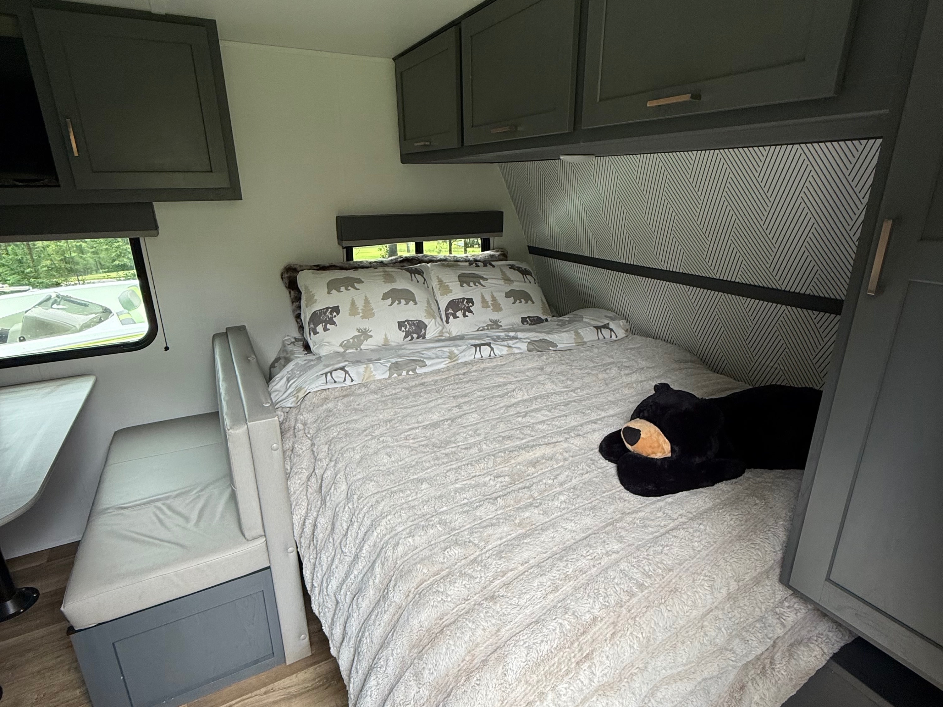 Cozy rv rental bedroom and dinette area, featuring bear-themed bedding, dark cabinets, and wood-look flooring.. Keystone RV Bullet Crossfire 2024