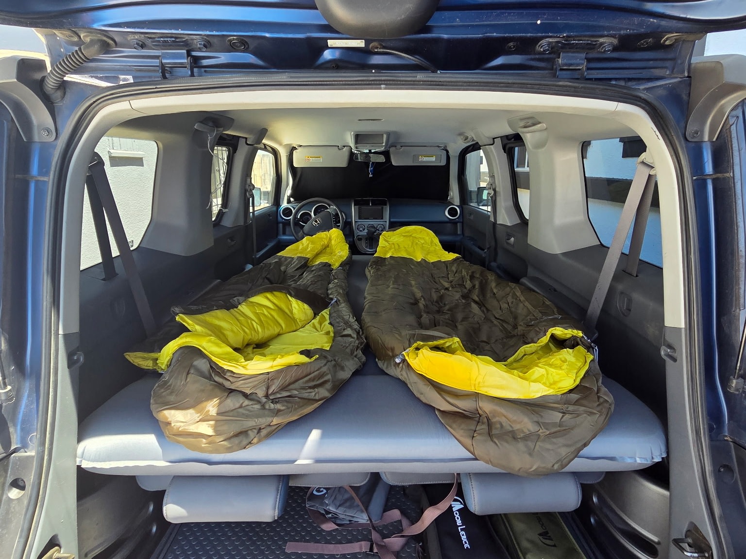 RV rental alternative: Vehicle interior set up for car camping with two sleeping bags on an air mattress.. Honda Element 2003