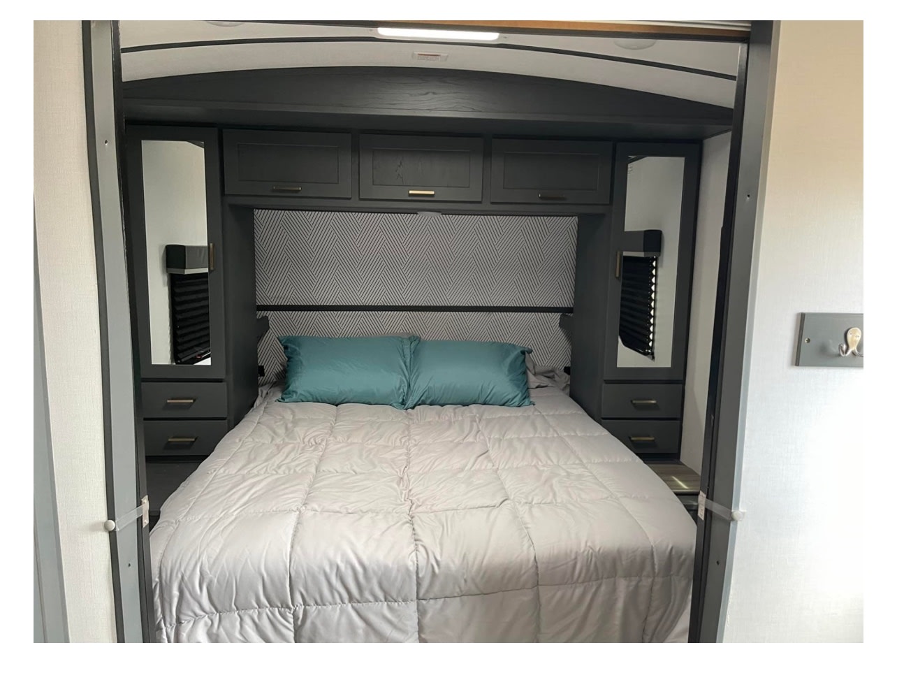 Cozy RV rental bedroom with modern grey decor, a queen bed, and ample storage cabinets for a comfortable stay.. Keystone RV Bullet Ultra Lite 2022