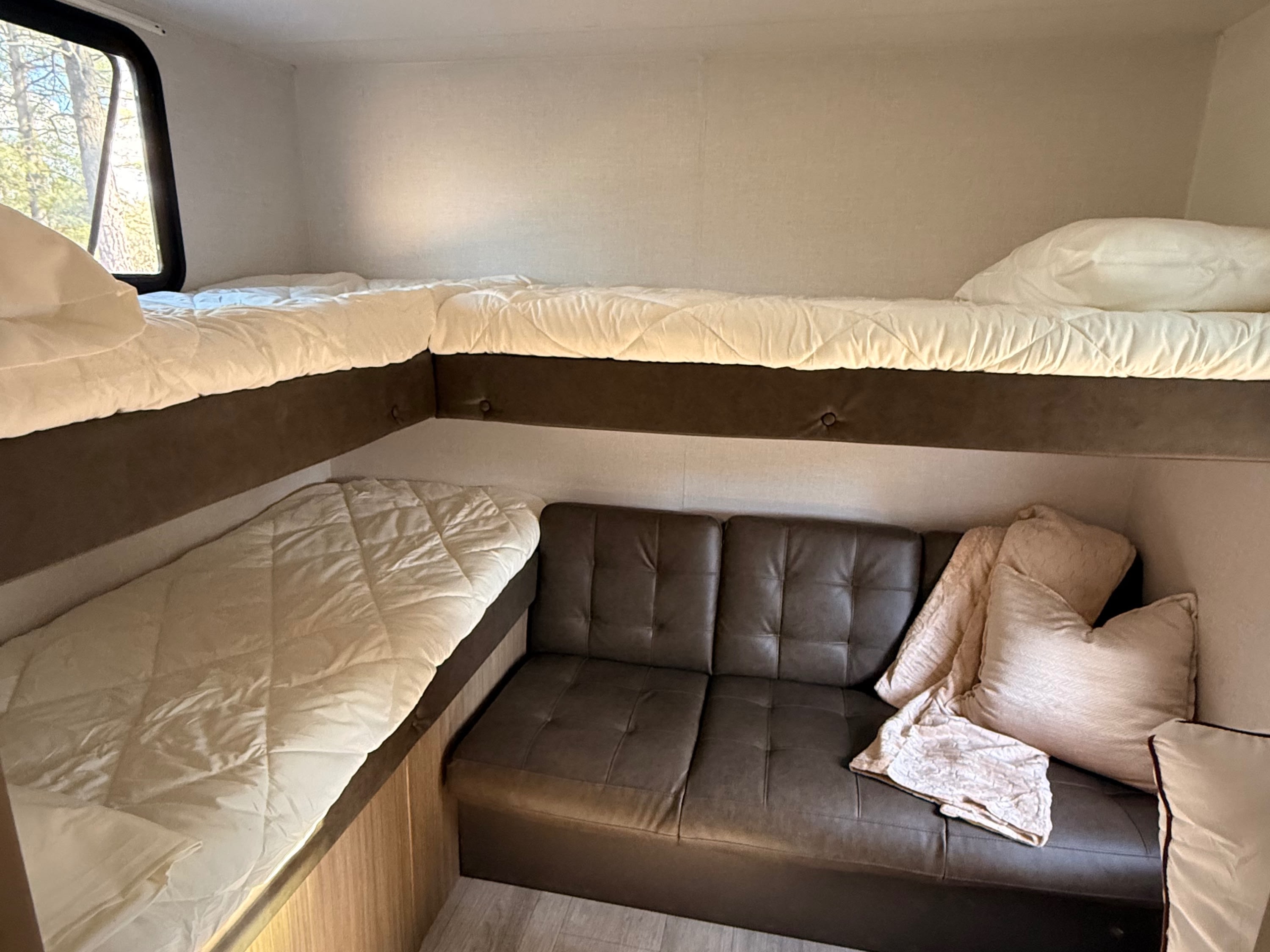 RV rental bunkhouse: features comfortable bunk beds, a cozy sofa, and a window for scenic views, ideal for family travel.. Forest River Wildwood X-Lite 2025