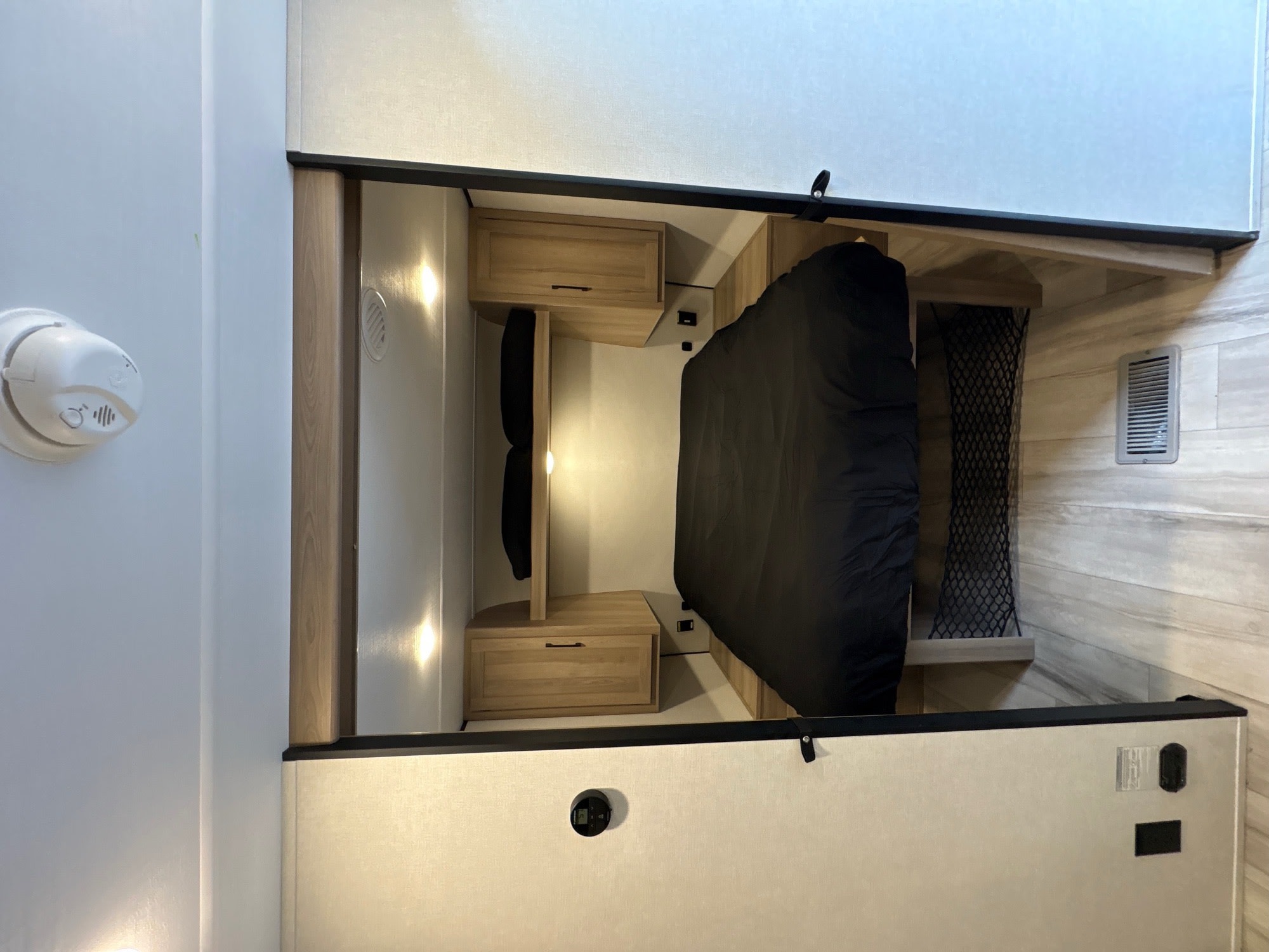 Cozy RV rental bedroom with black bedding, overhead cabinets, and climate control, perfect for your next adventure.. Coleman Light 26BX 2025