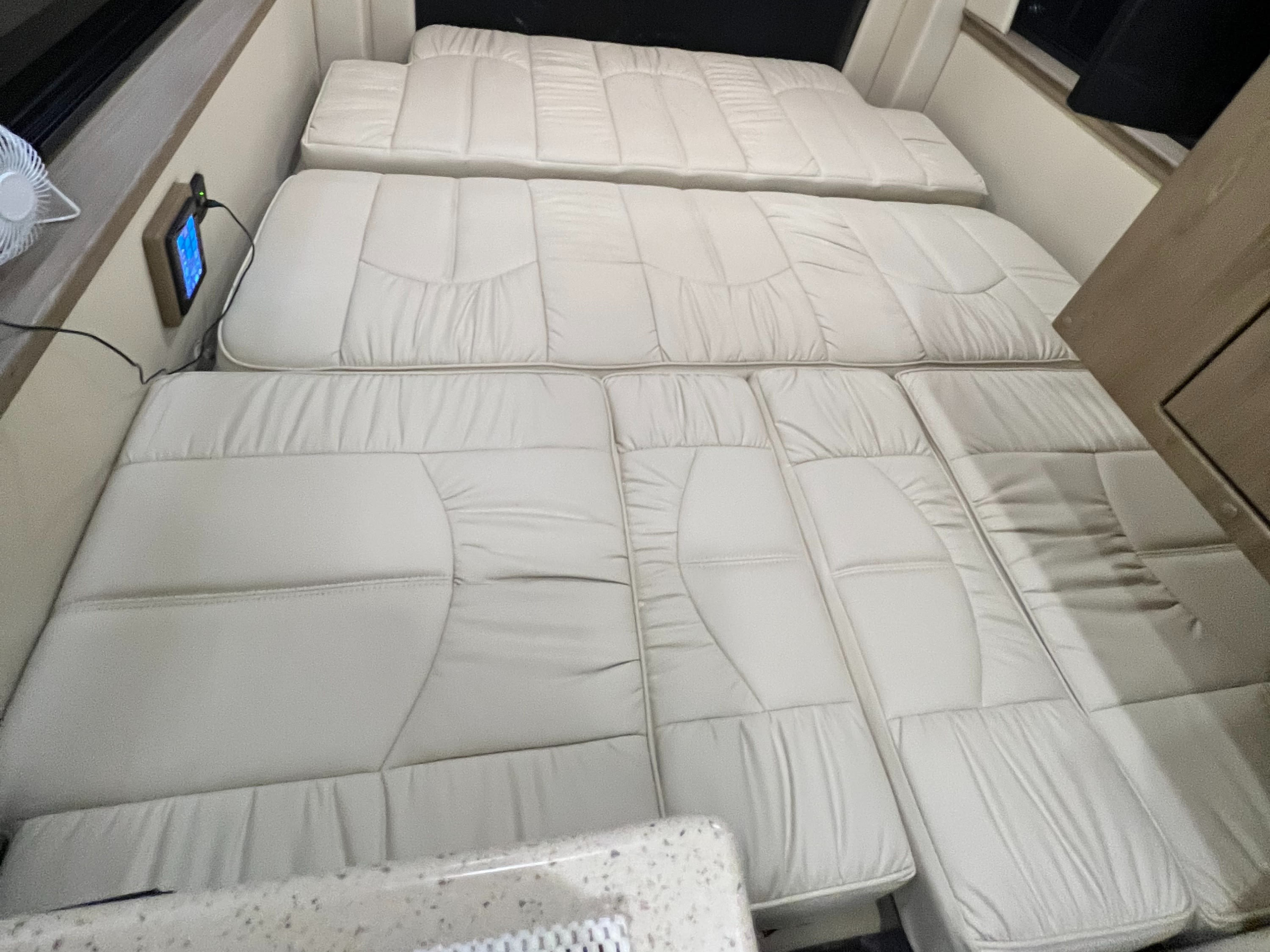 Spacious RV rental interior featuring light-colored cushions arranged as a bed, with windows & control panel access.. Midwest Automotive Designs Midwest Automotive Designs Class B 2021