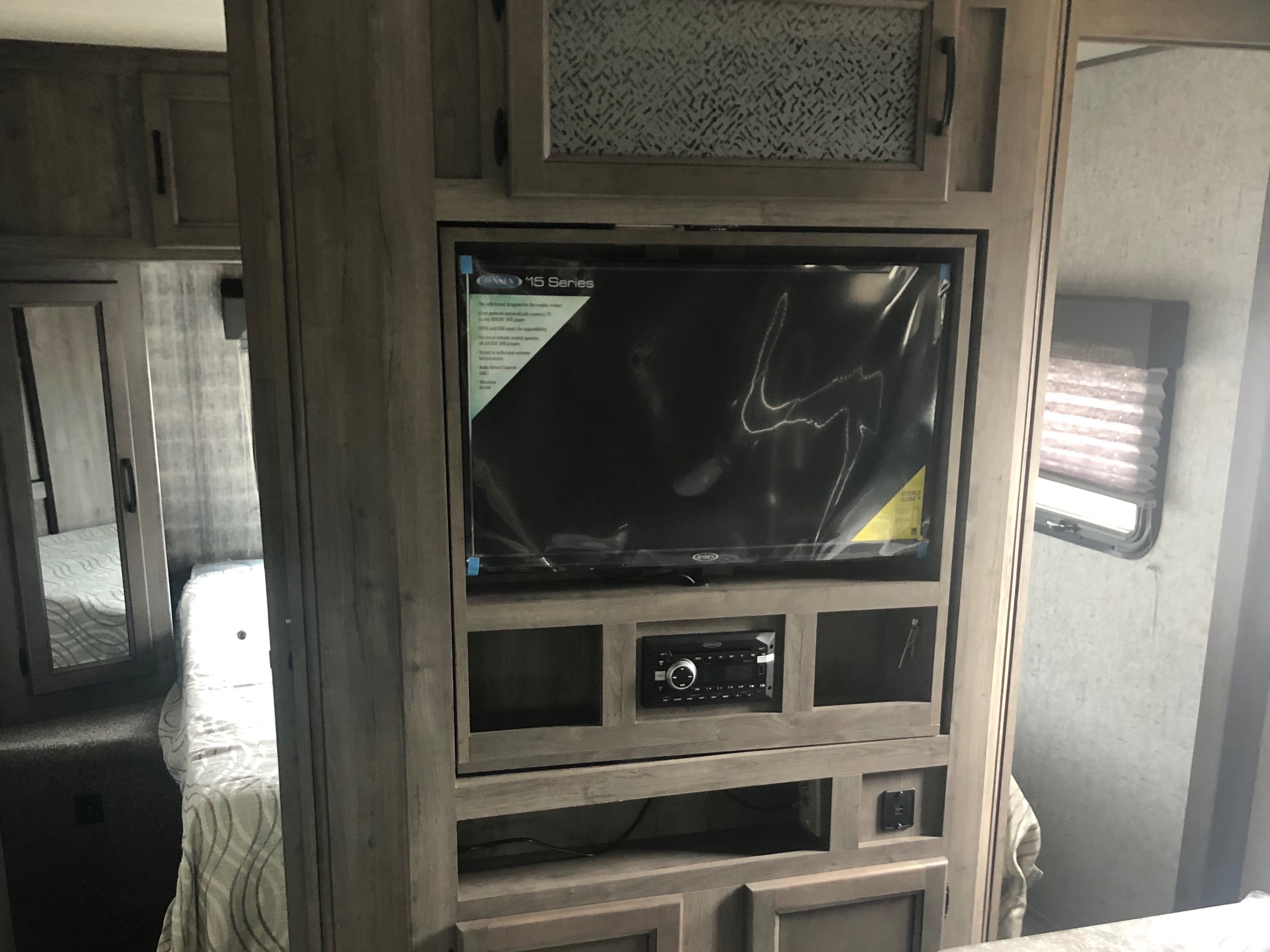 RV rental interior: modern entertainment center with TV & stereo, adjacent to a cozy bedroom area.. Coachmen Apex 2019