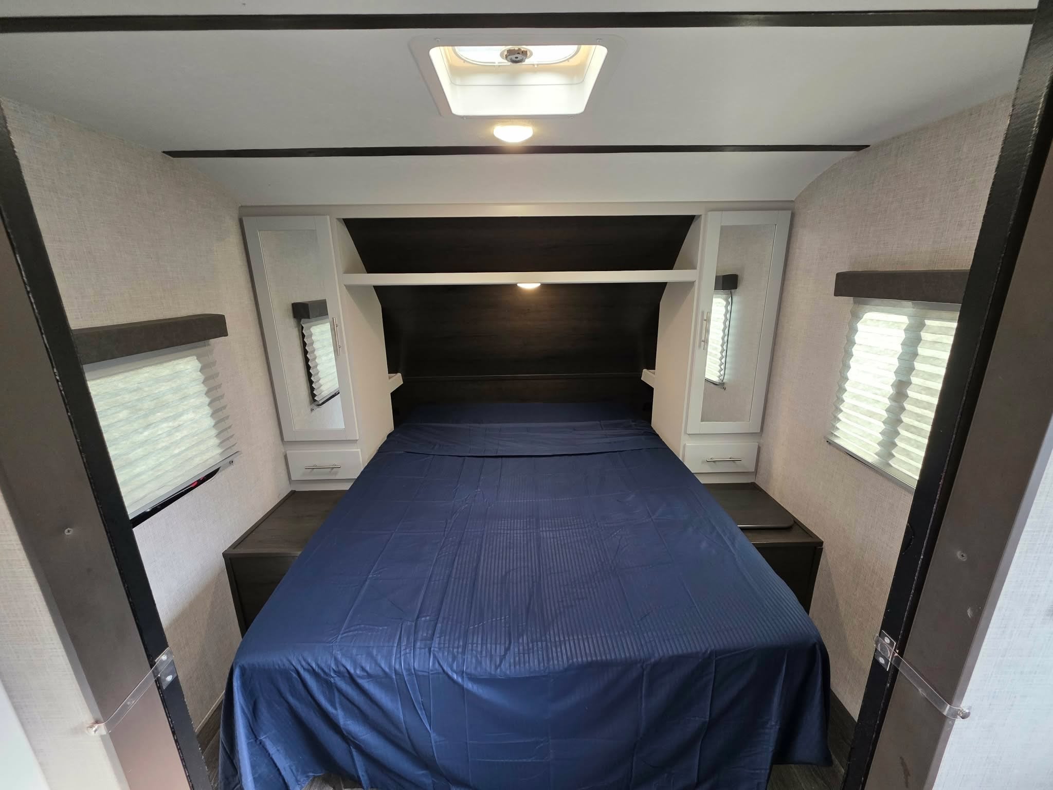 RV rental bedroom: cozy space with a large bed, headboard storage, and windows. Ideal for comfortable travel.. Keystone RV Bullet Ultra Lite 2021