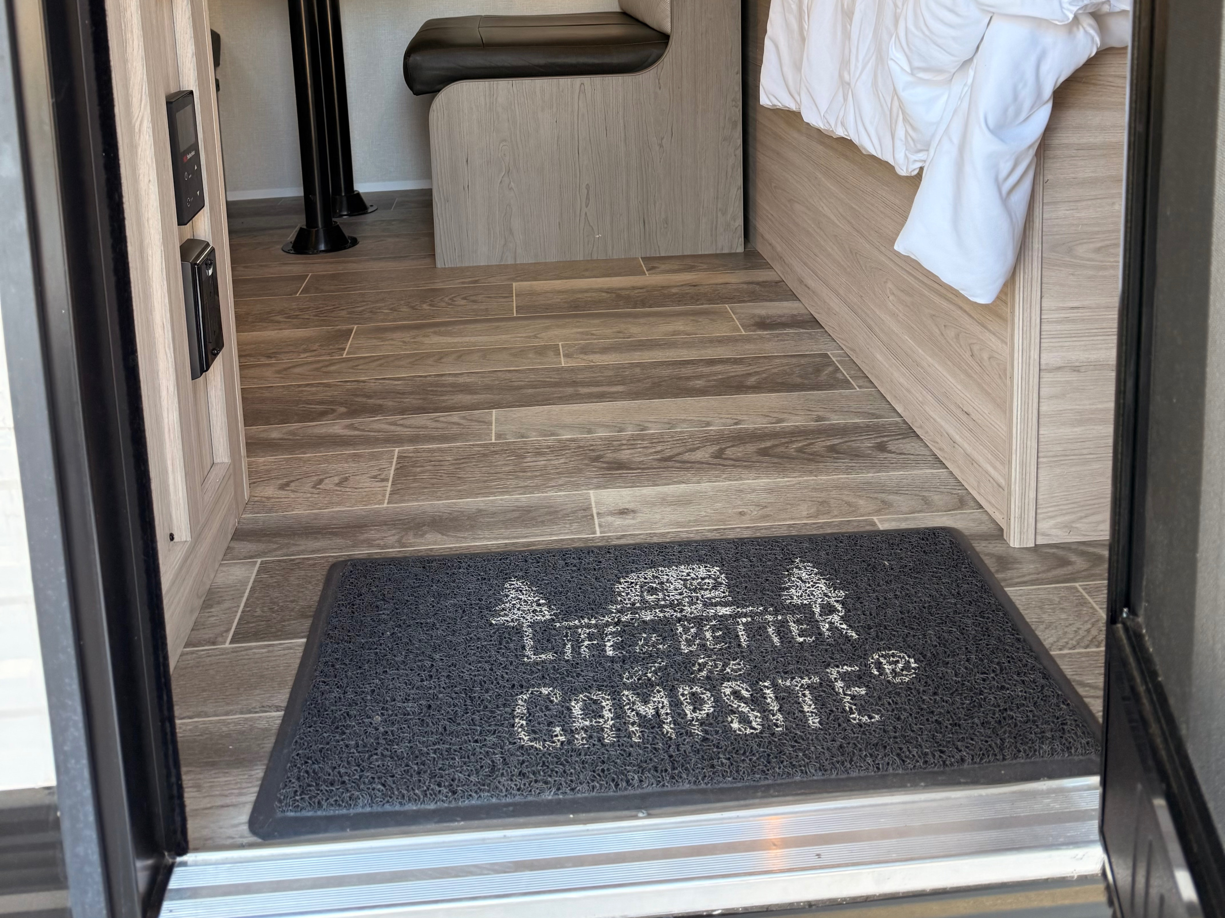 RV rental interior: A 'Life is Better at the Campsite' doormat welcomes you to wood-look flooring, dinette, and bed.. Heartland RVs Pioneer 2025