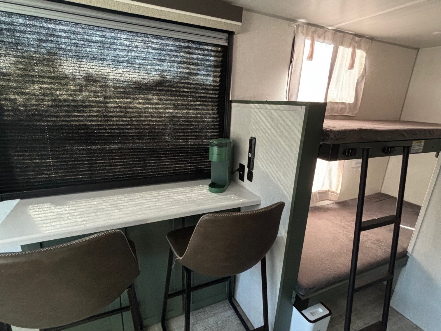 Cozy rv rental interior: modern workspace with window, two stools, and built-in bunk beds for efficient living.. No Boundaries 18 2025