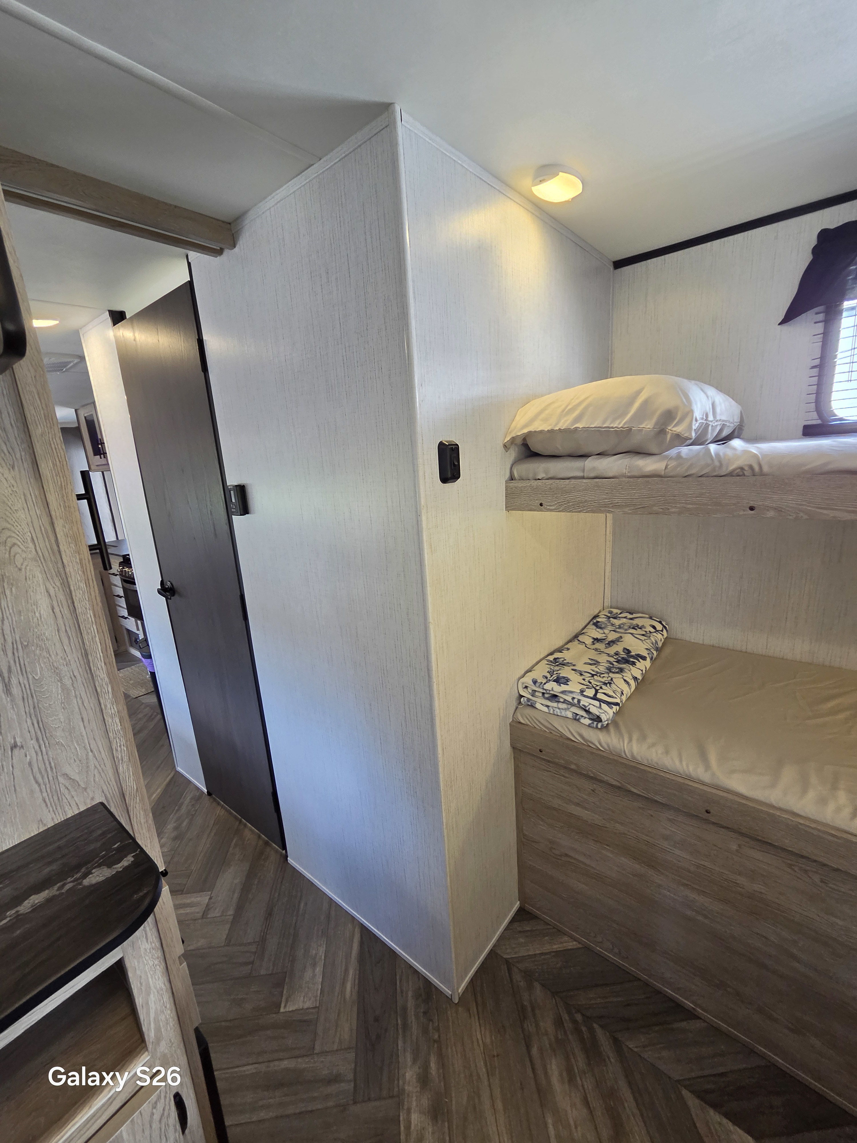 RV rental interior view showcasing cozy bunk beds, textured light walls, and attractive herringbone flooring.. Heartland RVs Prowler 2022