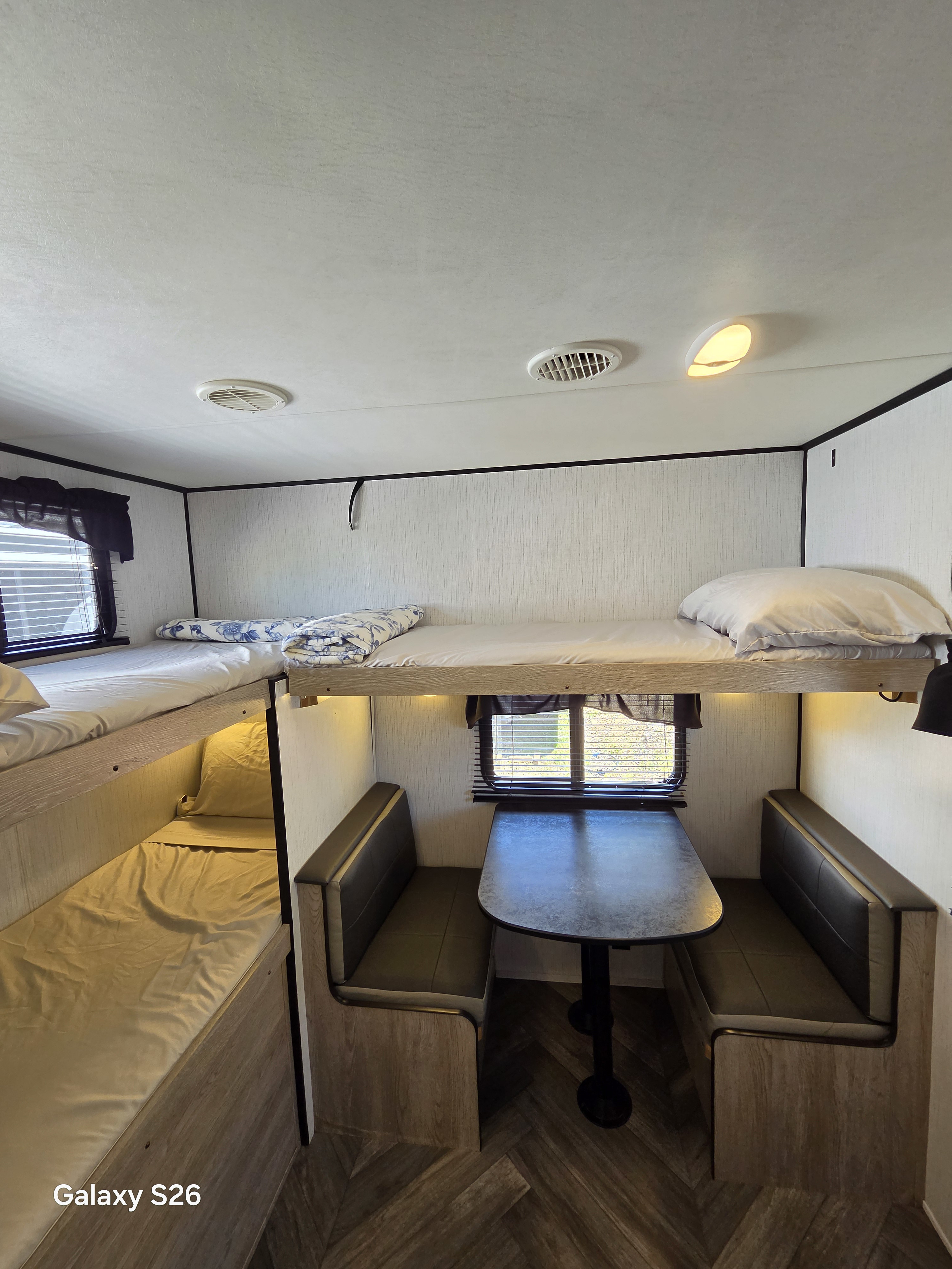 Cozy RV rental interior with bunk beds and a dinette. Bright lighting illuminates this compact, functional space.. Heartland RVs Prowler 2022