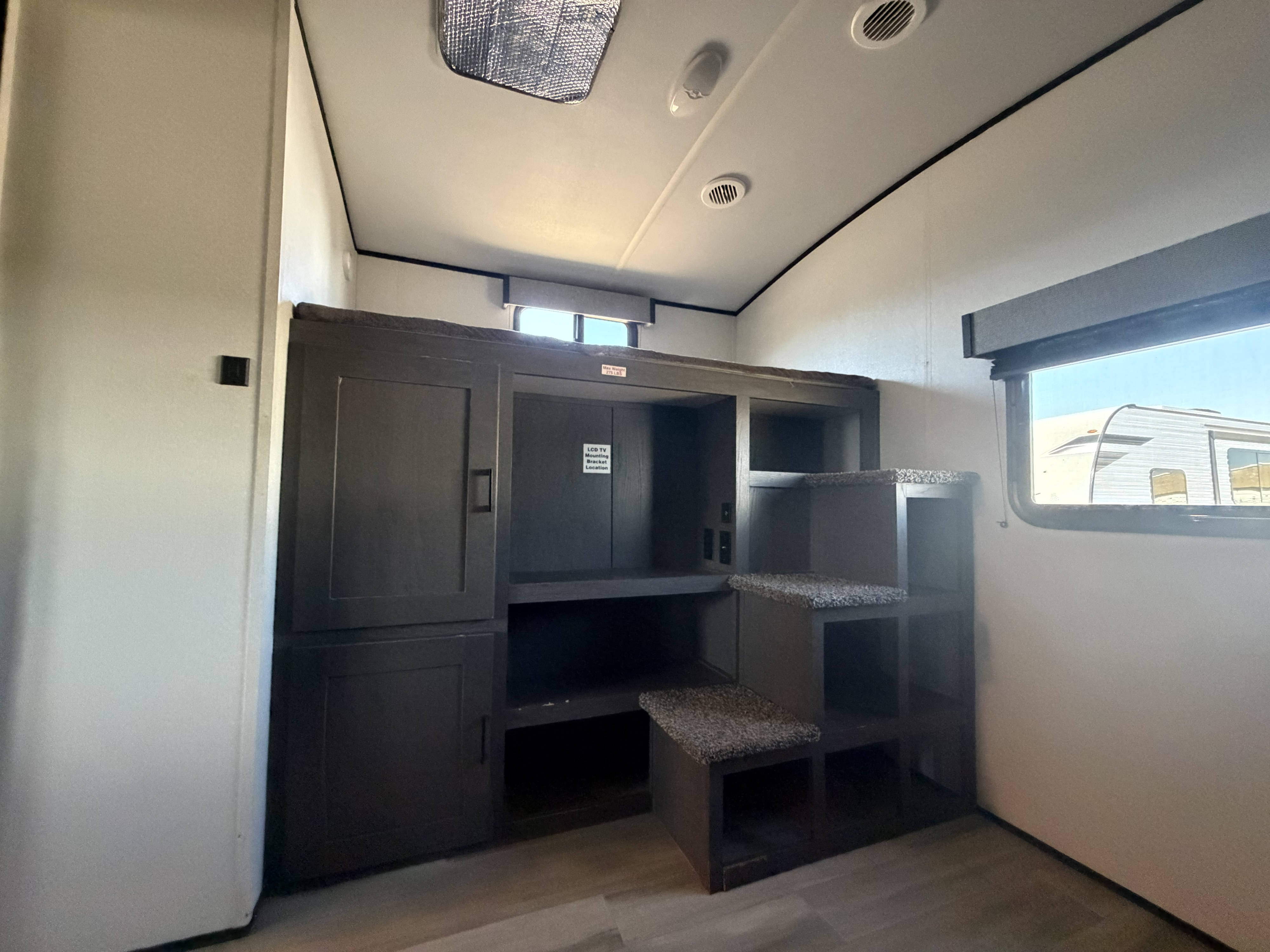 Cozy RV rental interior featuring built-in bunk beds with steps, ample storage cabinets, and a dedicated TV mounting area.. Cruiser RV MPG Ultra Lite 2021