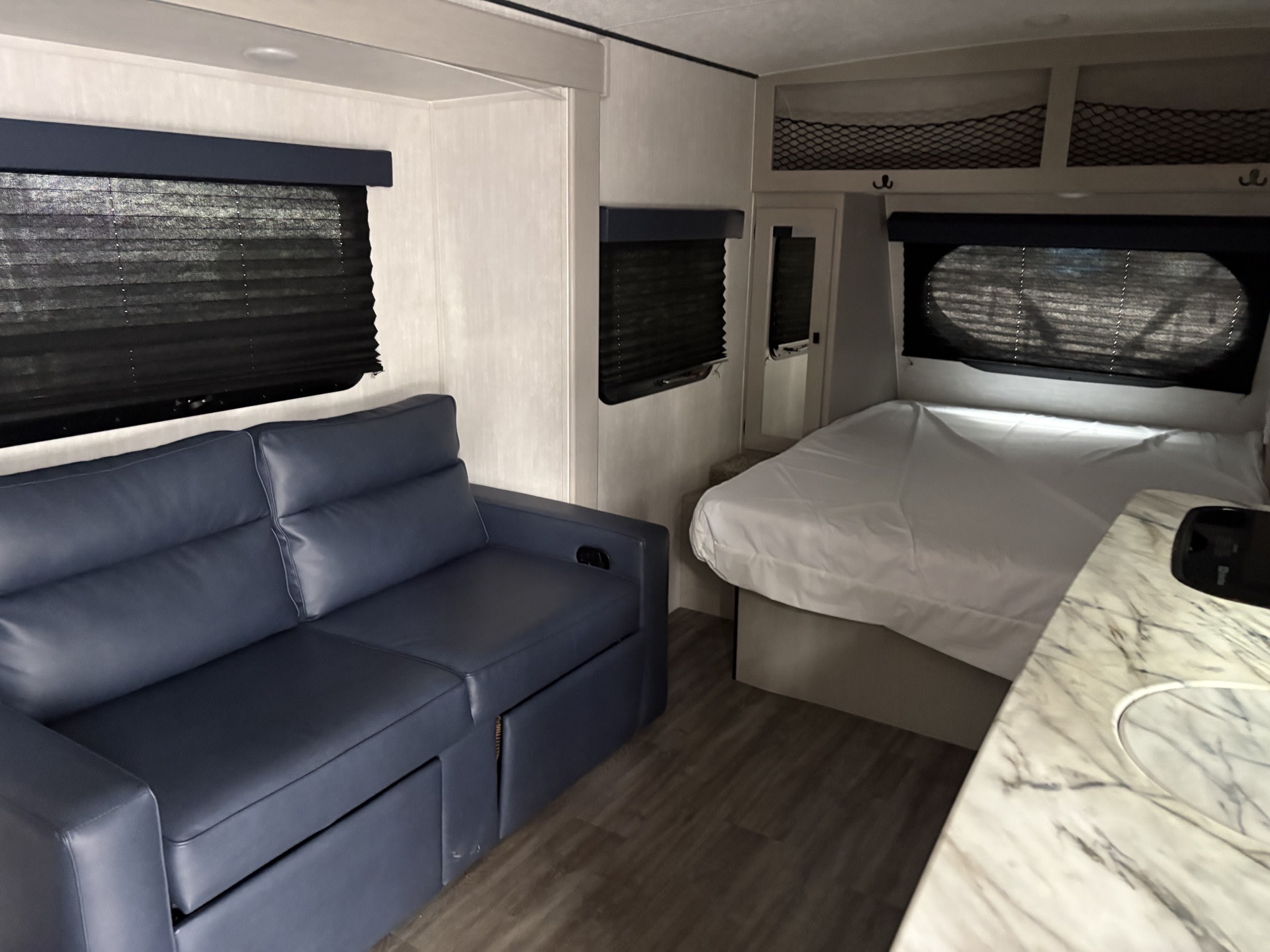 Relax in this rv rental's interior, featuring a blue sofa, cozy bed with white linens, and practical counter space.. Coachmen Other 2024