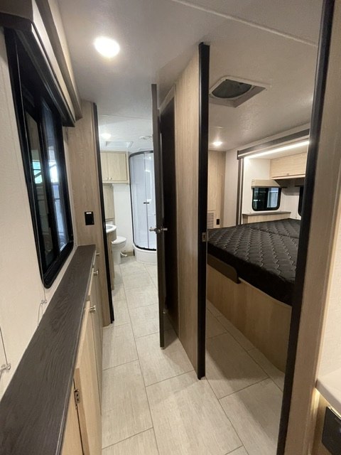 Inside a modern RV rental: hallway, bathroom with shower, and bedroom. Clean and bright travel.. Coachmen LEPERCHAUN 308KB 2027