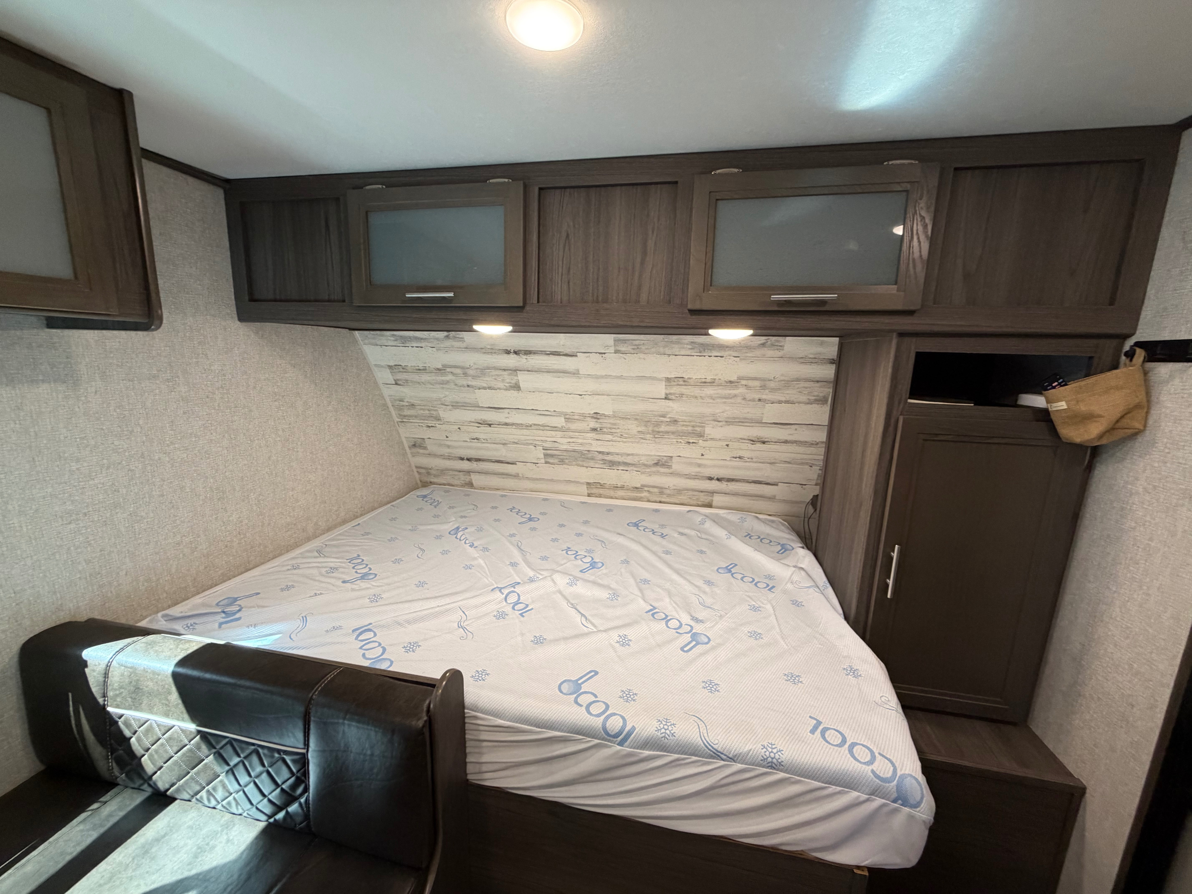 RV rental bedroom featuring a comfortable bed with a cooling mattress, overhead cabinets, and a side wardrobe for storage.. Dutchmen Kodiak Cub 2021