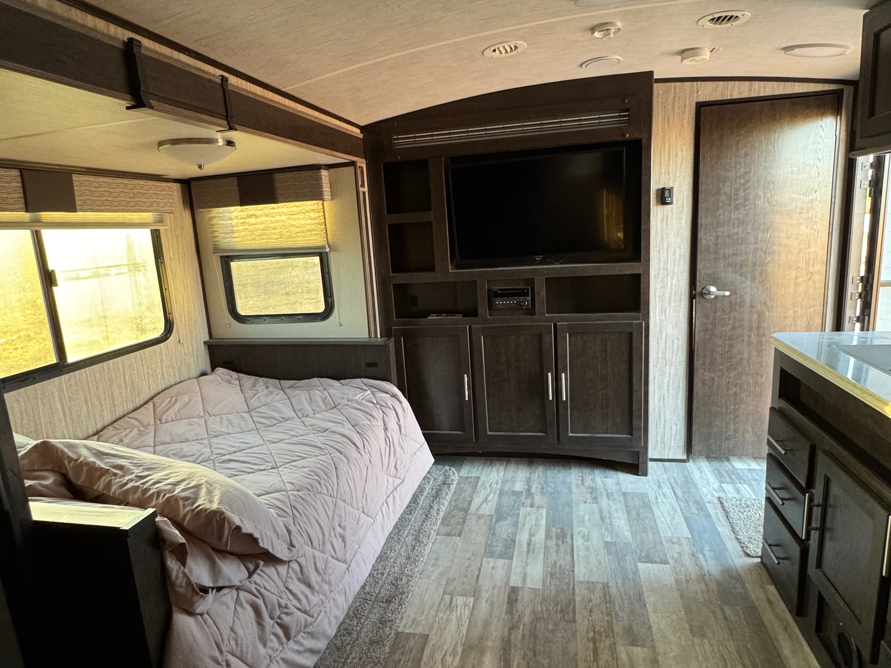 Cozy rv rental interior featuring a comfy bed, entertainment center, windows with blinds, and stylish wooden finishes.. Cruiser RV Fun Finder Xtreme Lite 2019