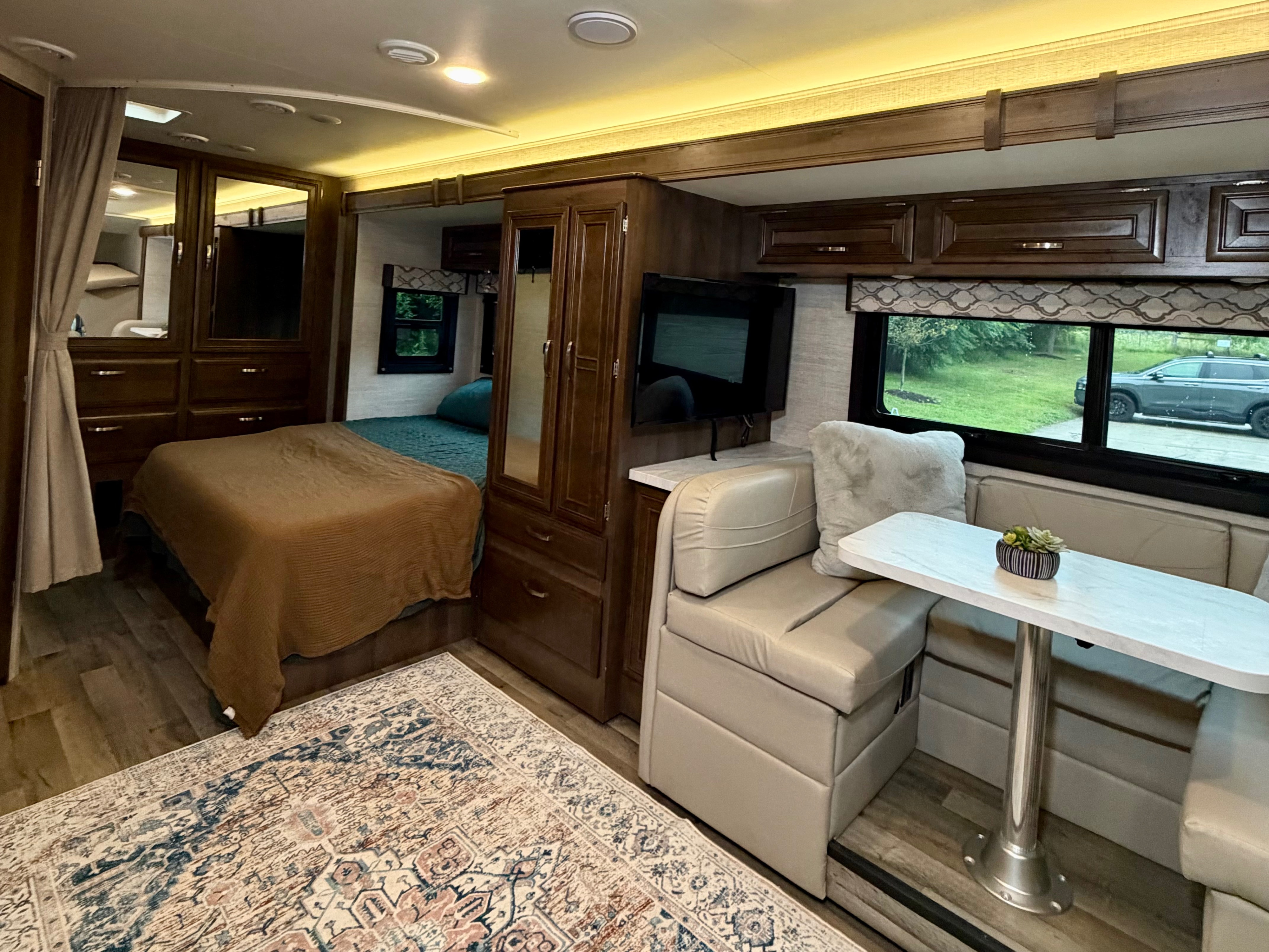 Cozy RV rental interior with a comfortable dinette, inviting bedroom, and wood-toned storage units.. Jayco Redhawk 2022