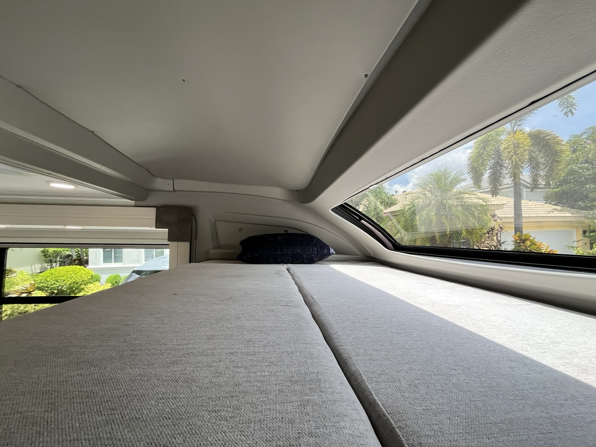 Cozy **rv rental** sleeping area with panoramic window showing palm trees and a sunny exterior.. Forest River Coachmen Prism Elite 2026
