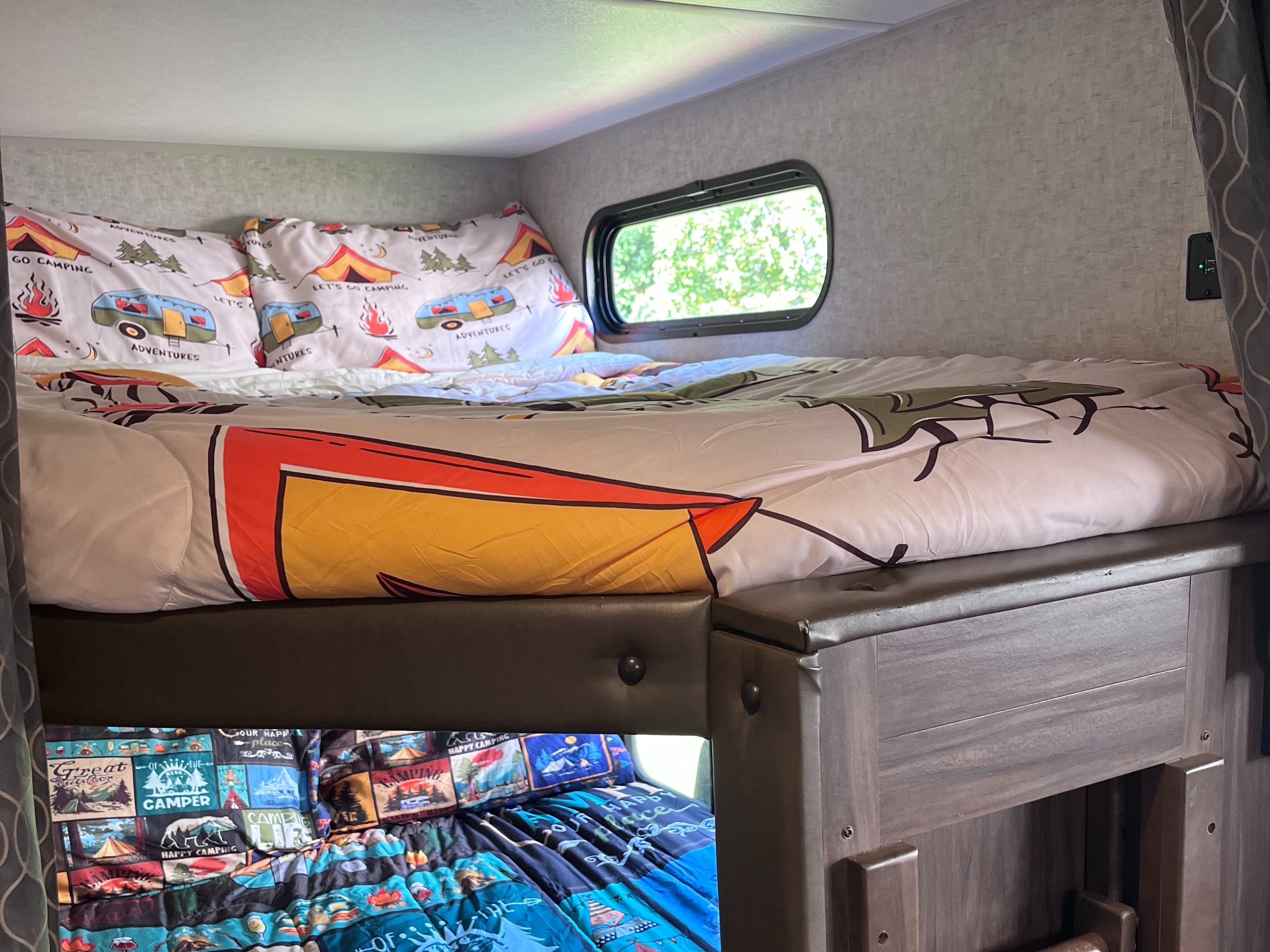 Cozy RV rental bunk beds featuring camping-themed bedding and a small window, providing comfortable accommodations for adventures.. Forest River Cherokee Grey Wolf 2018