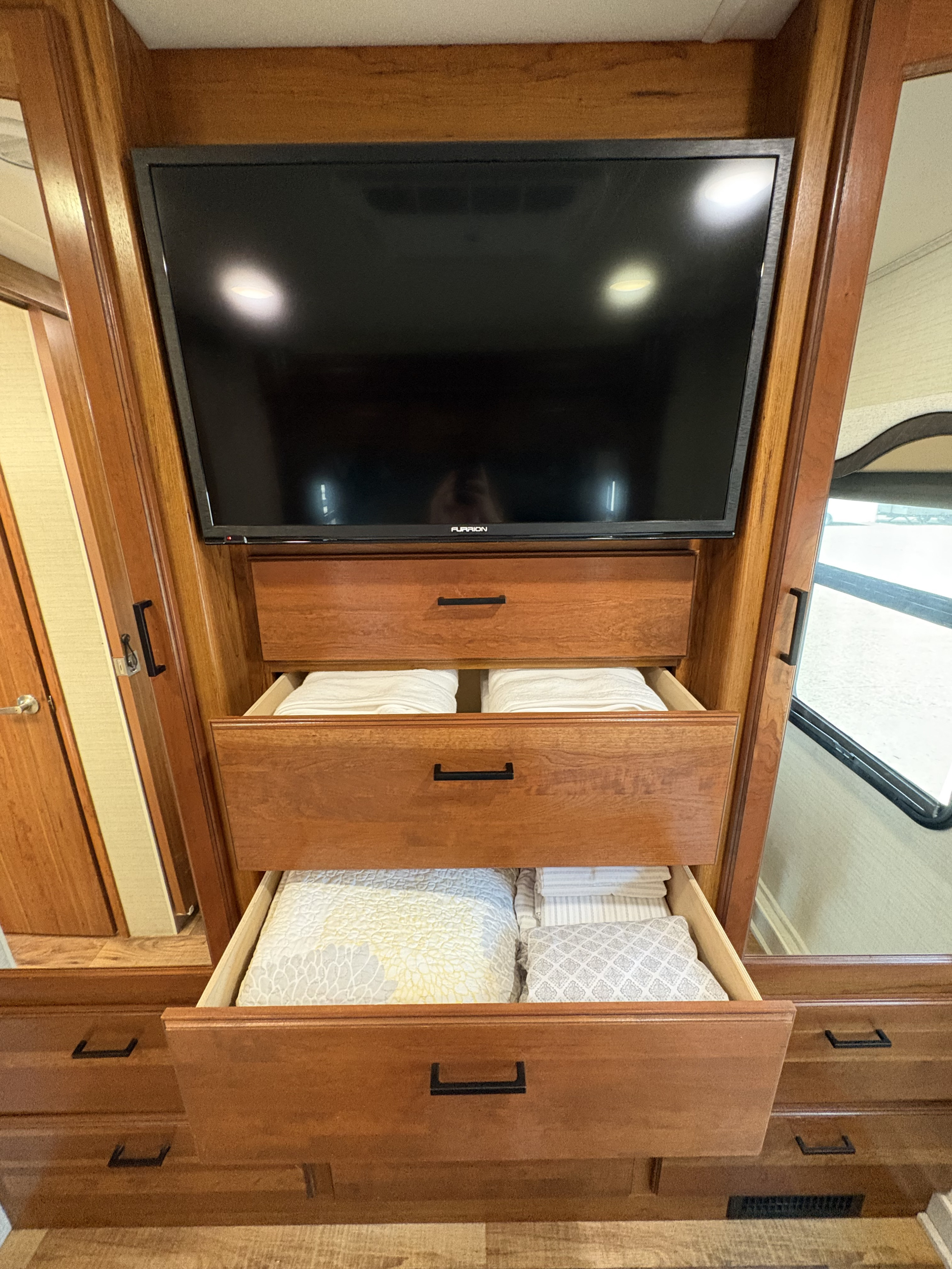 Neat RV rental bedroom storage: TV, and open wooden drawers with folded linens and bedding for convenient interior living.. Jayco Precept 2017