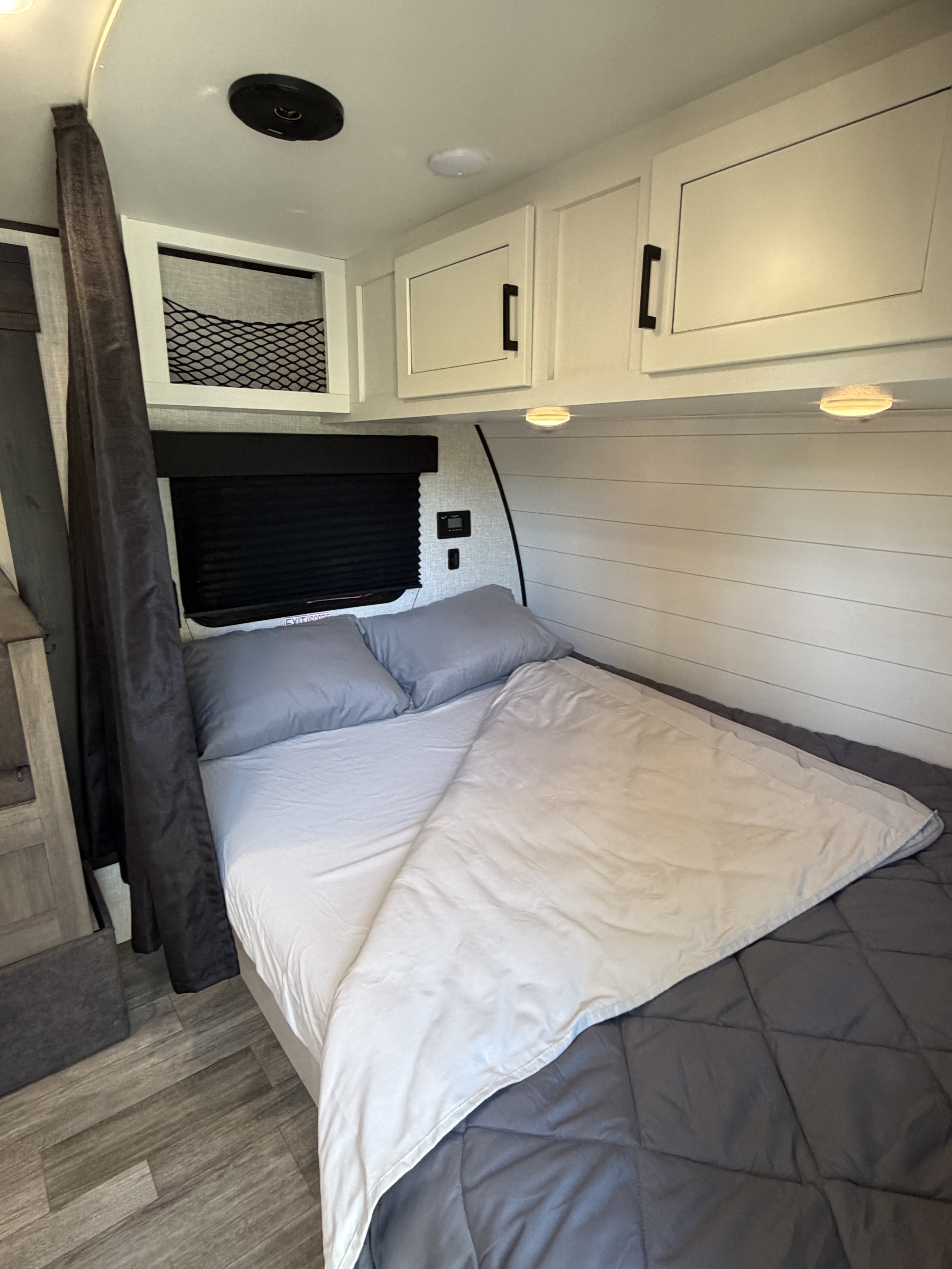 Cozy RV rental bedroom interior featuring a bed with gray bedding, white cabinets, and wood-look flooring.. Jayco Jay Flight SLX Baja Edition 2024
