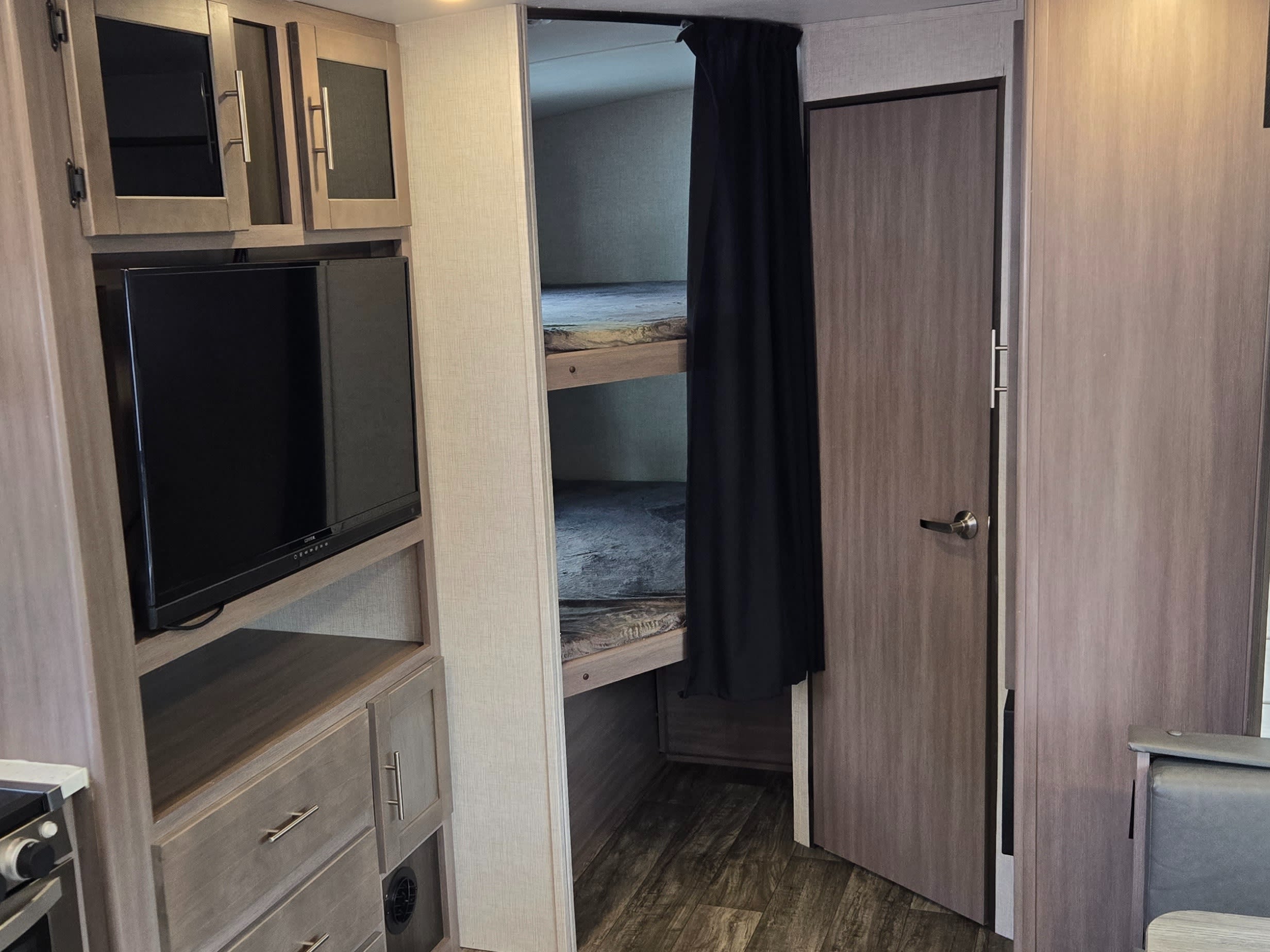 RV rental interior: kitchen, TV, bunk beds with curtain, and dining nook. Compact and functional living space.. Crossroads RV Sunset Trail Super Lite 2022