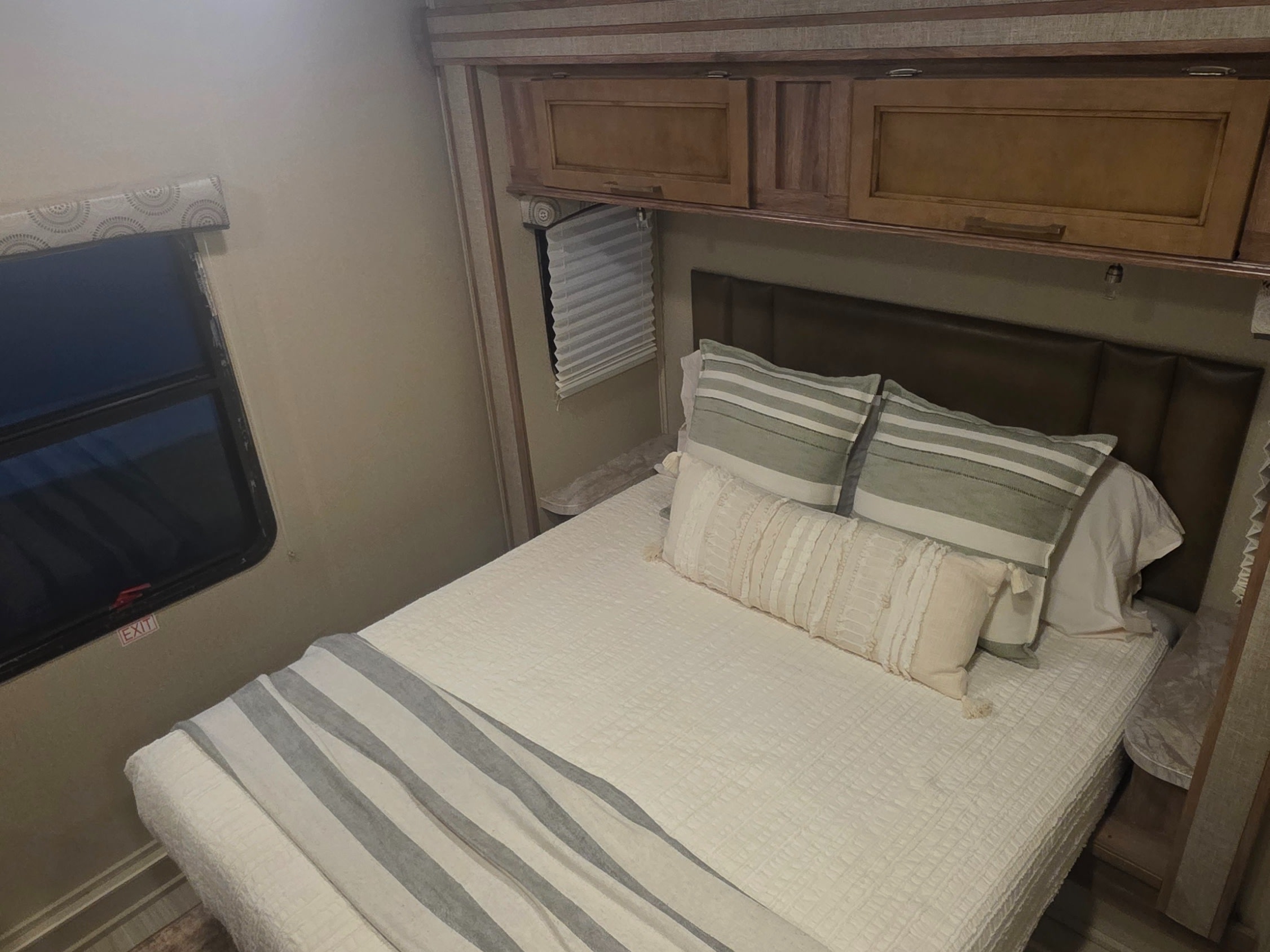 Cozy RV rental bedroom with a comfy bed, padded headboard, and storage cabinets. Perfect for a restful trip.. Entegra Coach Odyssey 2020