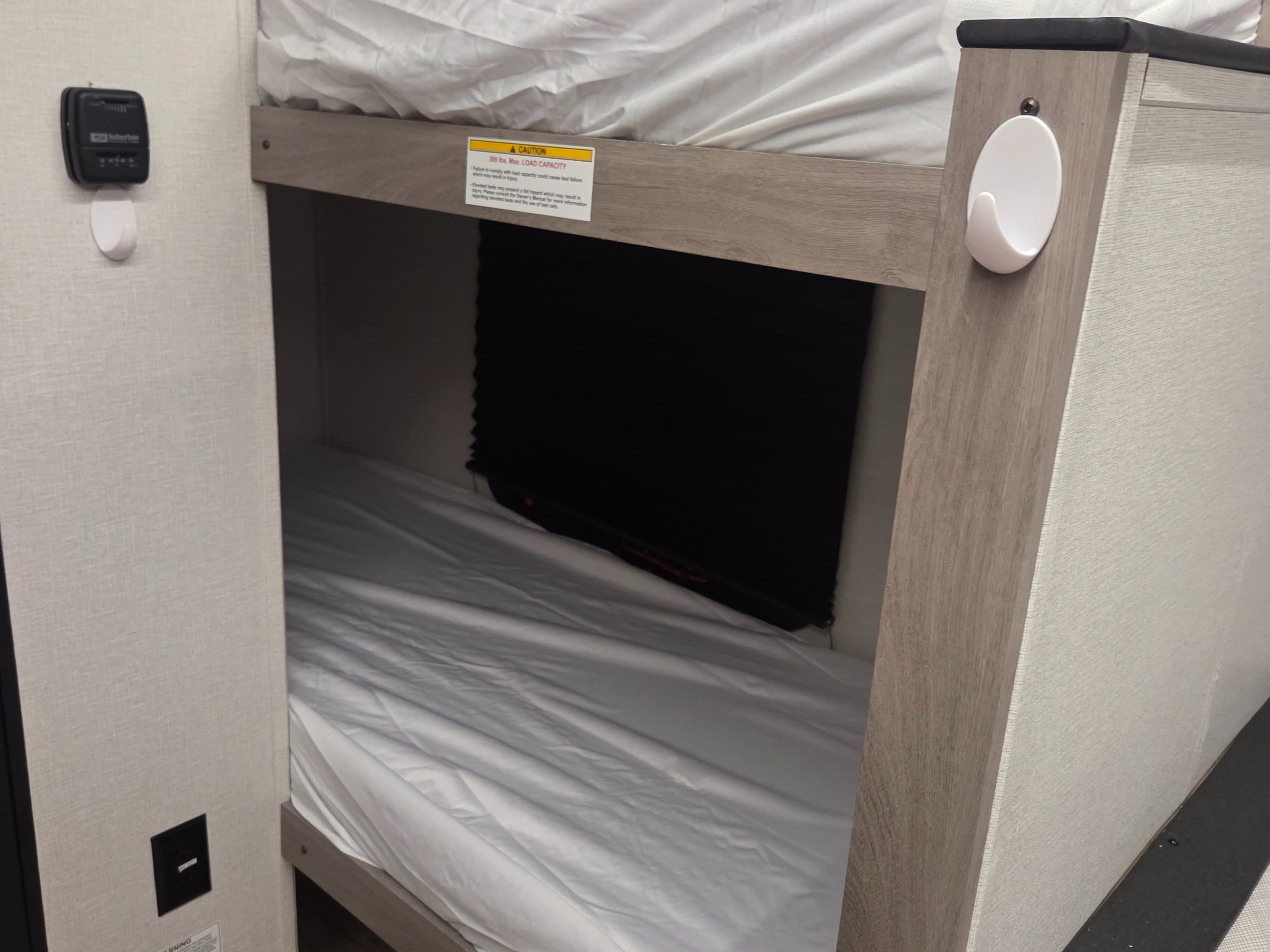 RV rental bunk beds with white sheets, a thermostat, and a warning label for 300 lbs. max load on the top bunk.. Cruiser RV Embrace 2025
