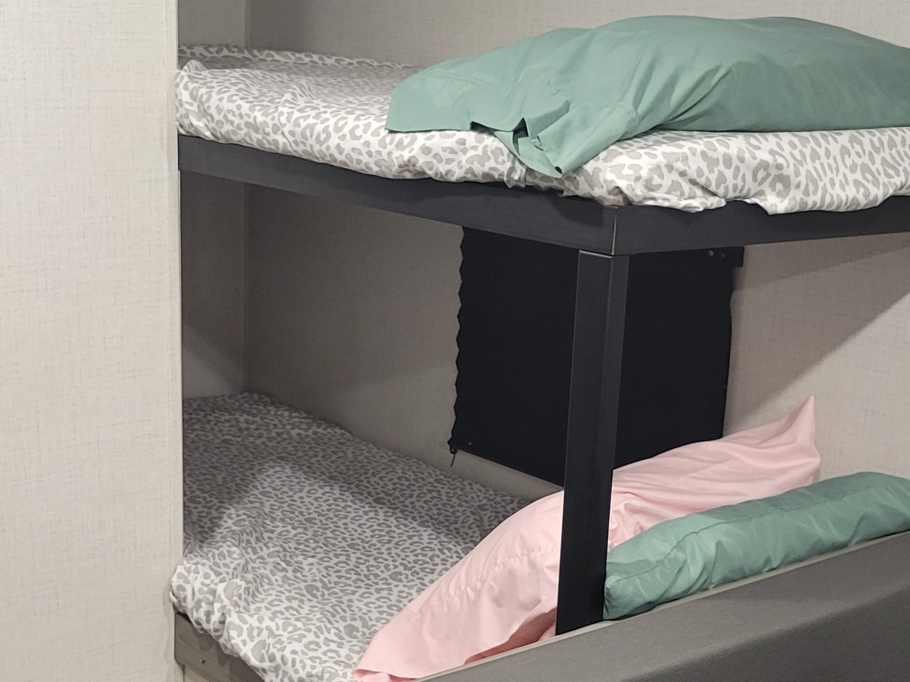 Cozy bunk beds in an RV rental, featuring leopard print bedding & colorful pillows.. Keystone RV Hideout 2024