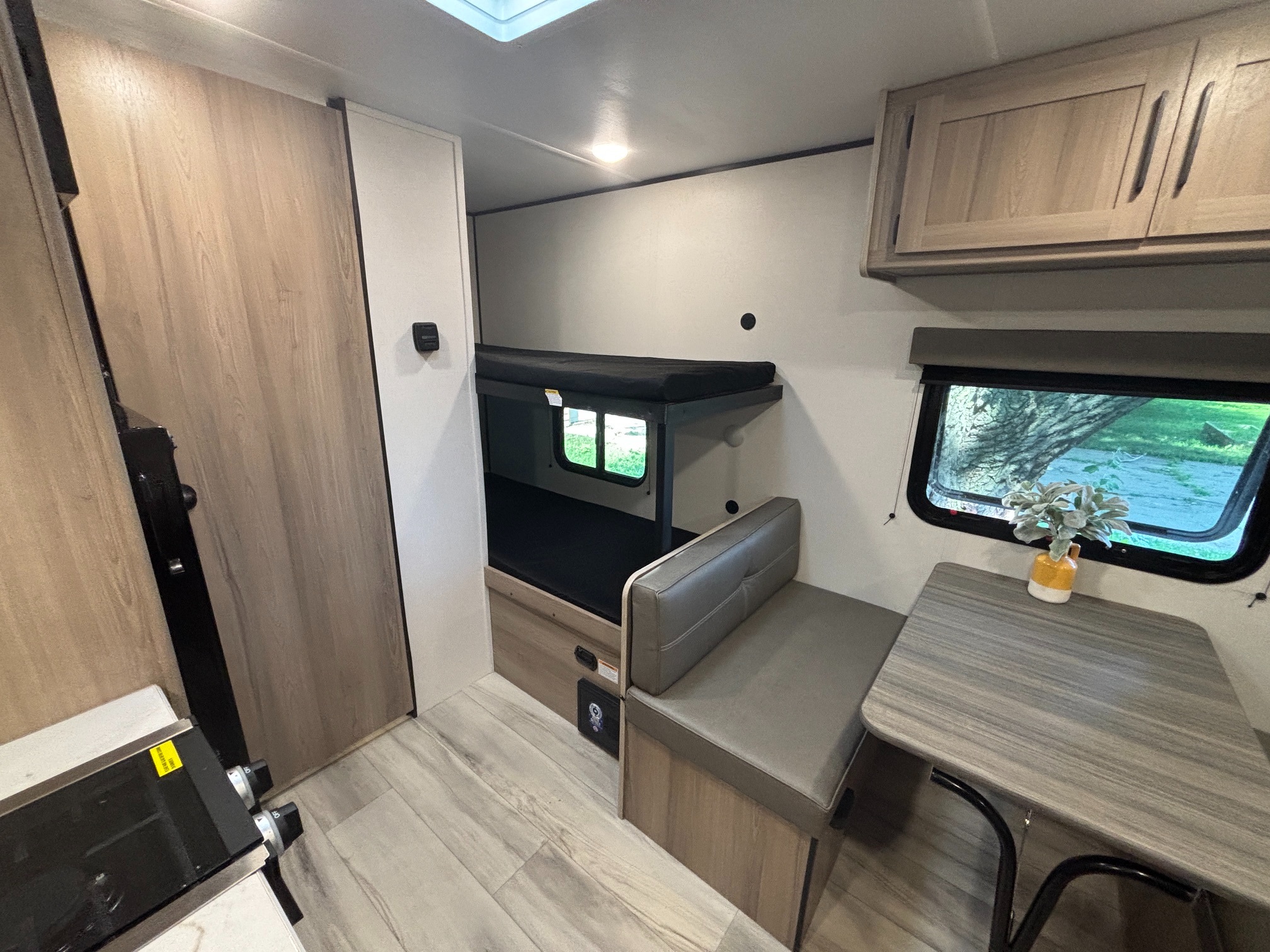 This inviting RV rental interior features bunk beds, a cozy dinette with seating & table, kitchen area, and overhead storage.. Keystone RV Coleman 2025