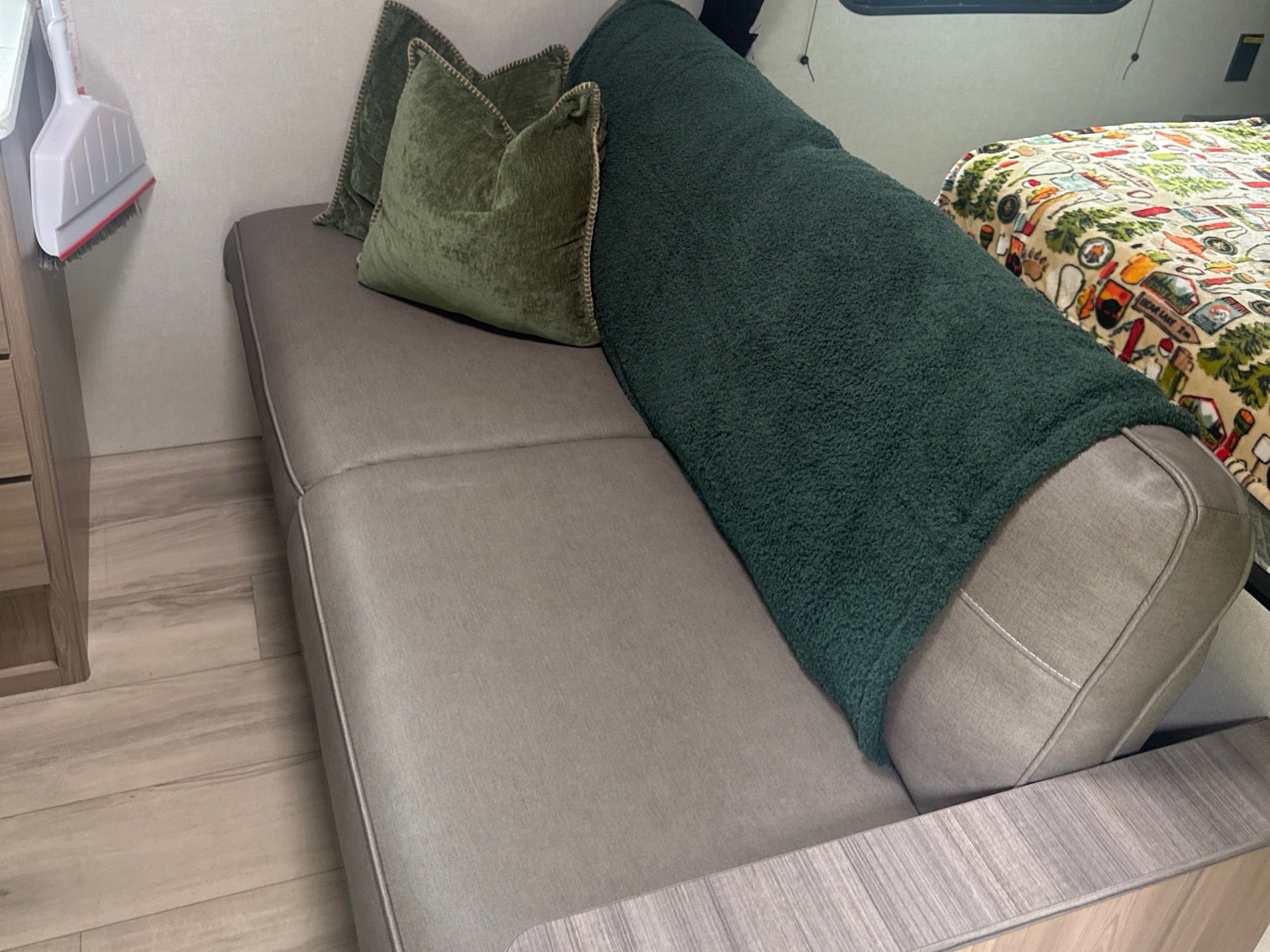 RV rental: interior sofa with green pillows/blanket, patterned bed, and efficient storage like the hanging broom.. Keystone RV Coleman 2025
