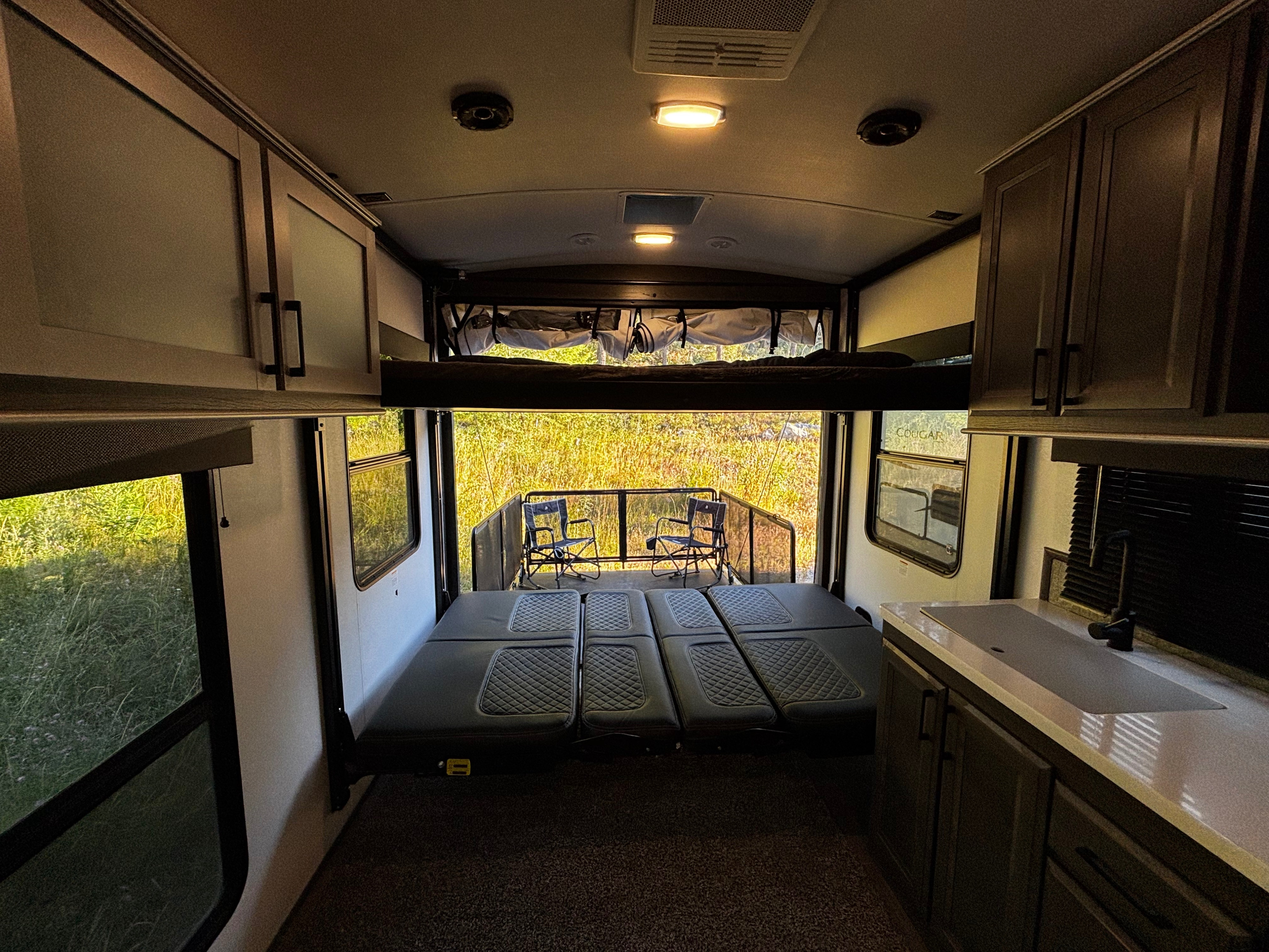 RV rental's adaptable garage: modular beds, overhead bunk, and open ramp leading to a patio with scenic views.. Cruiser Rv Corp Stryker 2021
