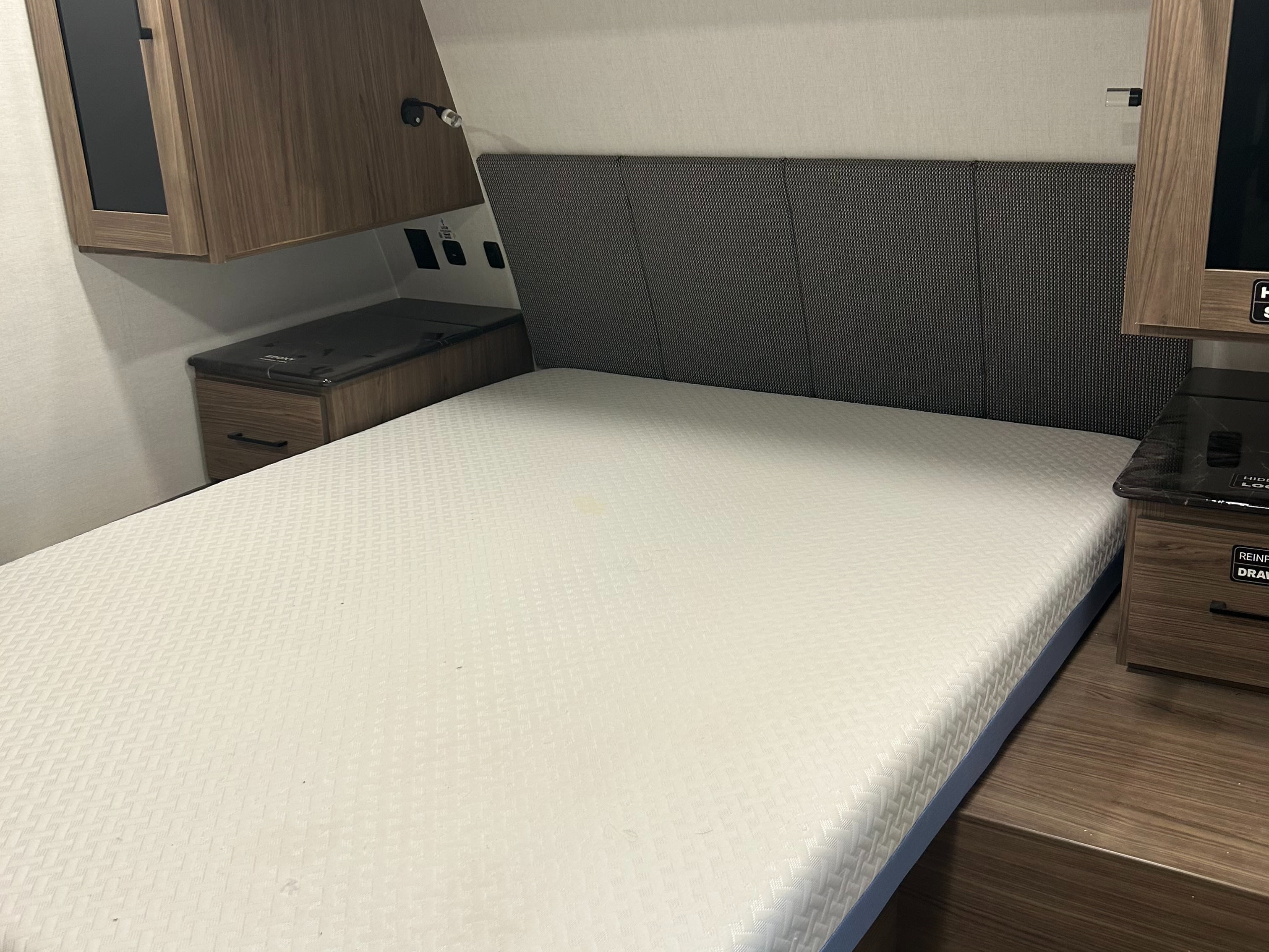 Cozy RV rental bedroom featuring a comfy mattress, modern headboard, and wood-look cabinetry with convenient power outlets.. Alliance RV Delta 2025
