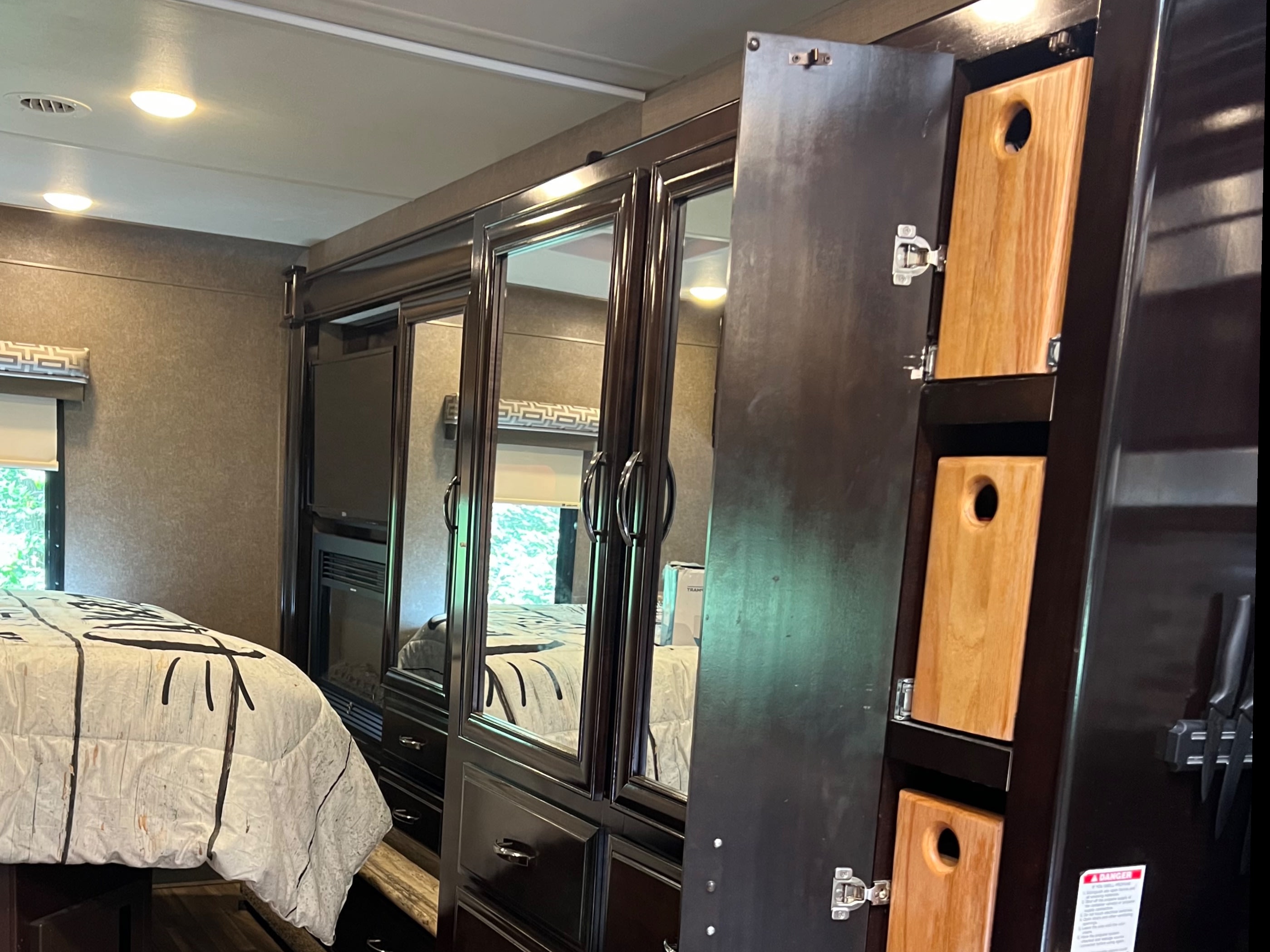 RV rental: Modern interior featuring a bed, dark wood cabinets, and clever kitchen storage with vertical cutting boards.. Thor Quantum 2017