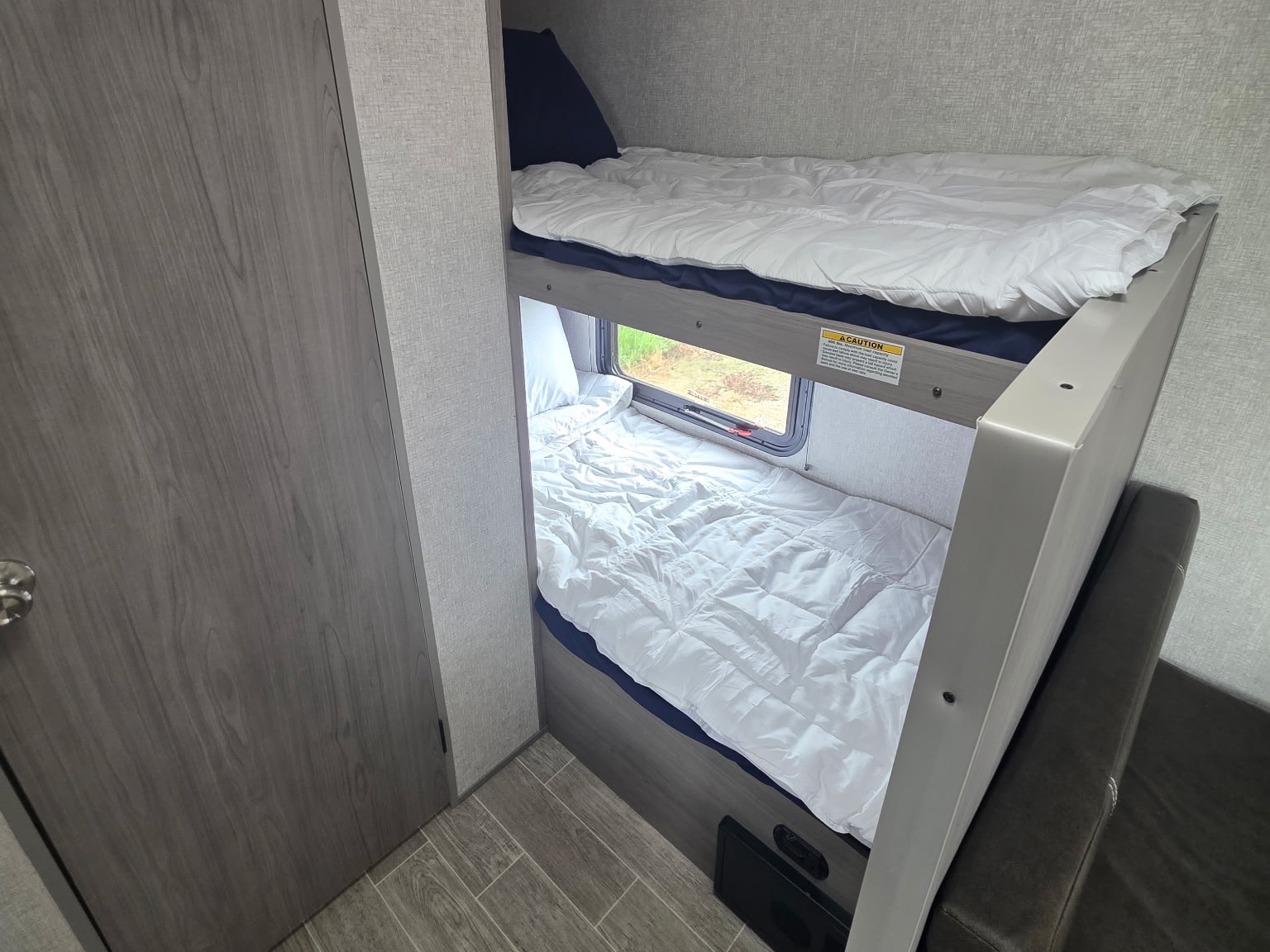 RV rental bunk beds provide cozy sleeping space inside a modern camper, with a window by the lower bunk.. Dutchmen Coleman Lantern LT 2022