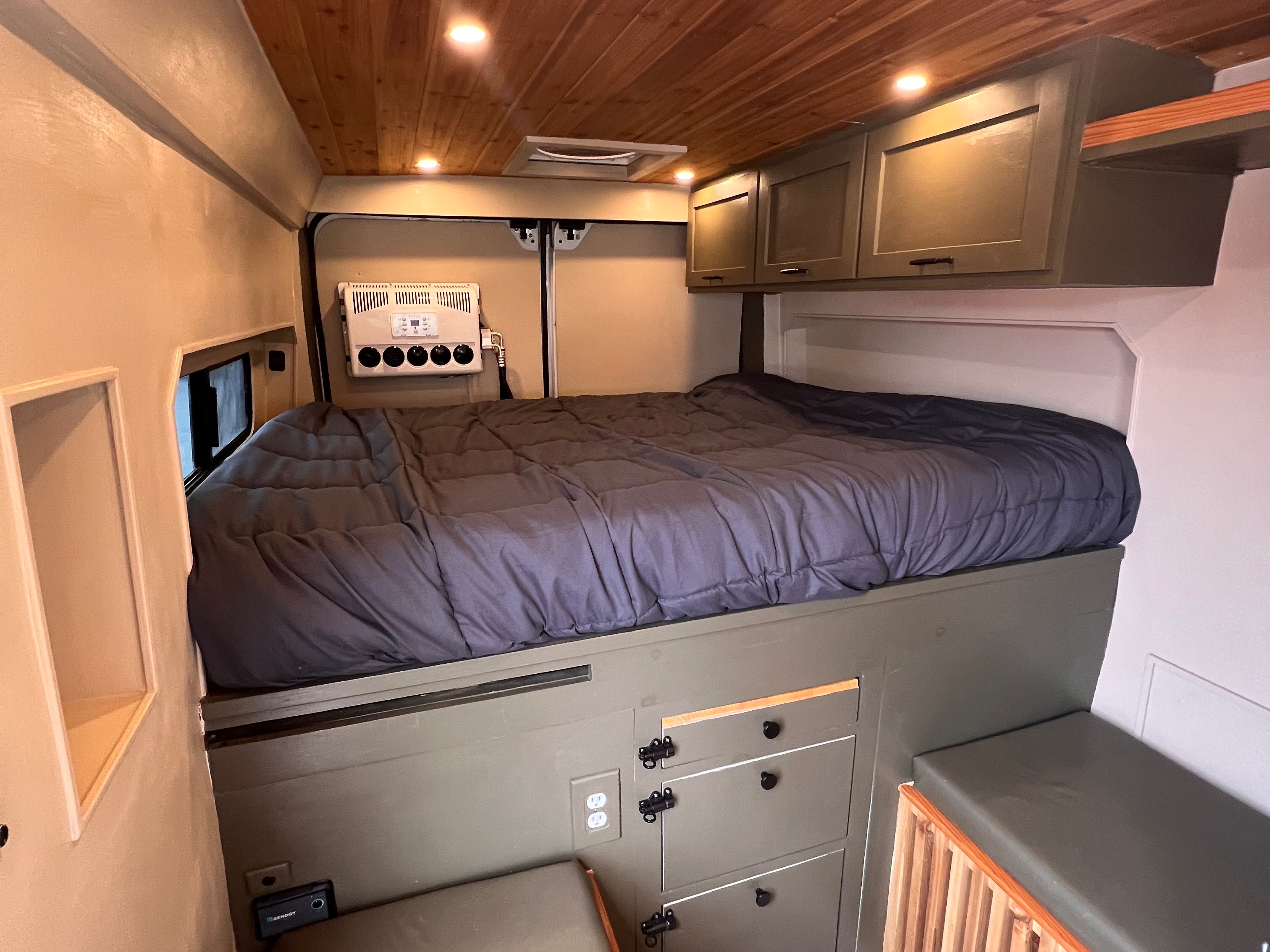 Explore this custom rv rental interior featuring a cozy bed, ample storage, climate control, and warm wooden accents.. Dodge Ram Promaster 2500 2020