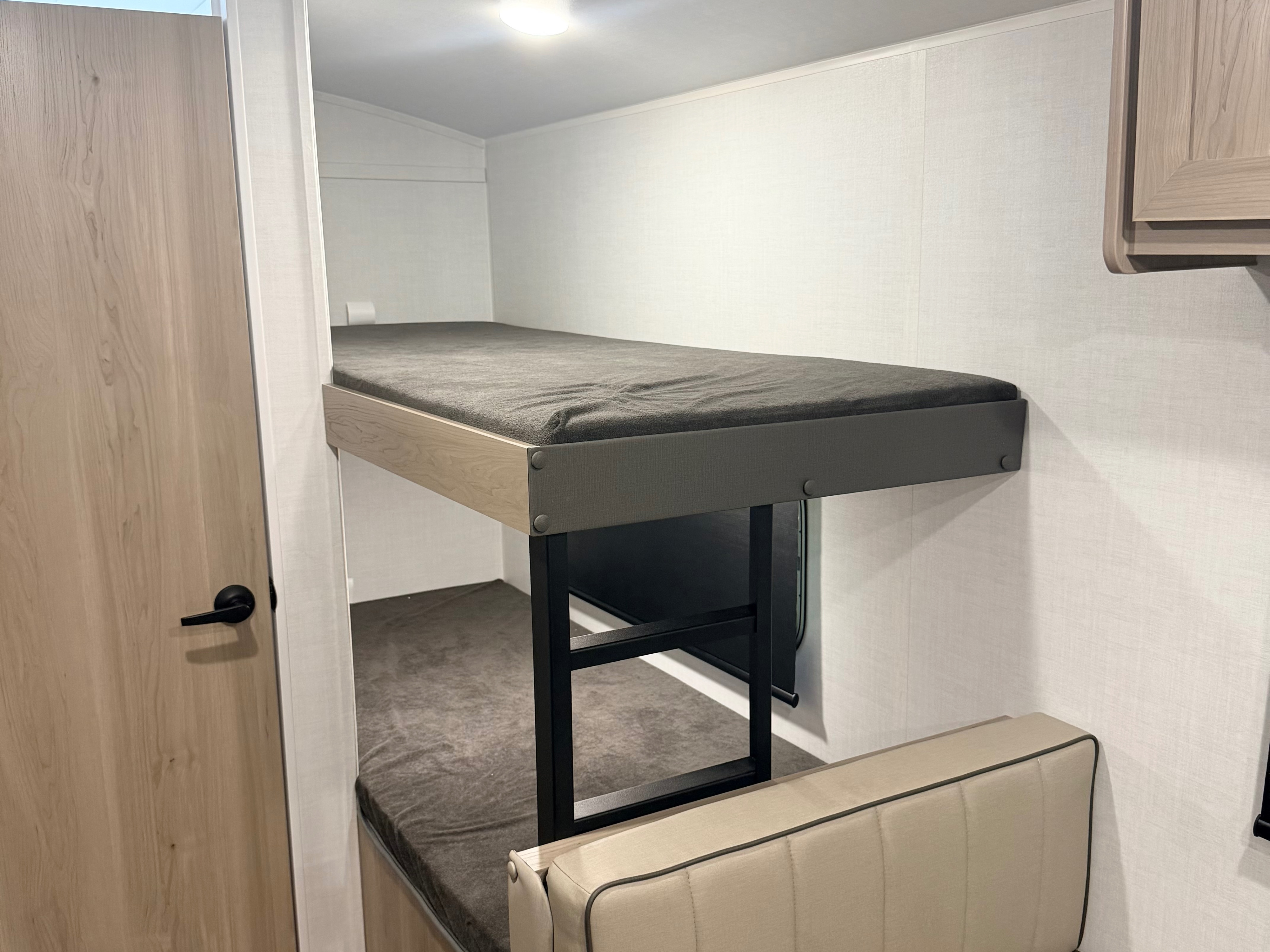 RV rental bunk beds and seating in a compact interior with light wood door and modern design.. Forest River Rockwood Geo Pro 17LE 2026