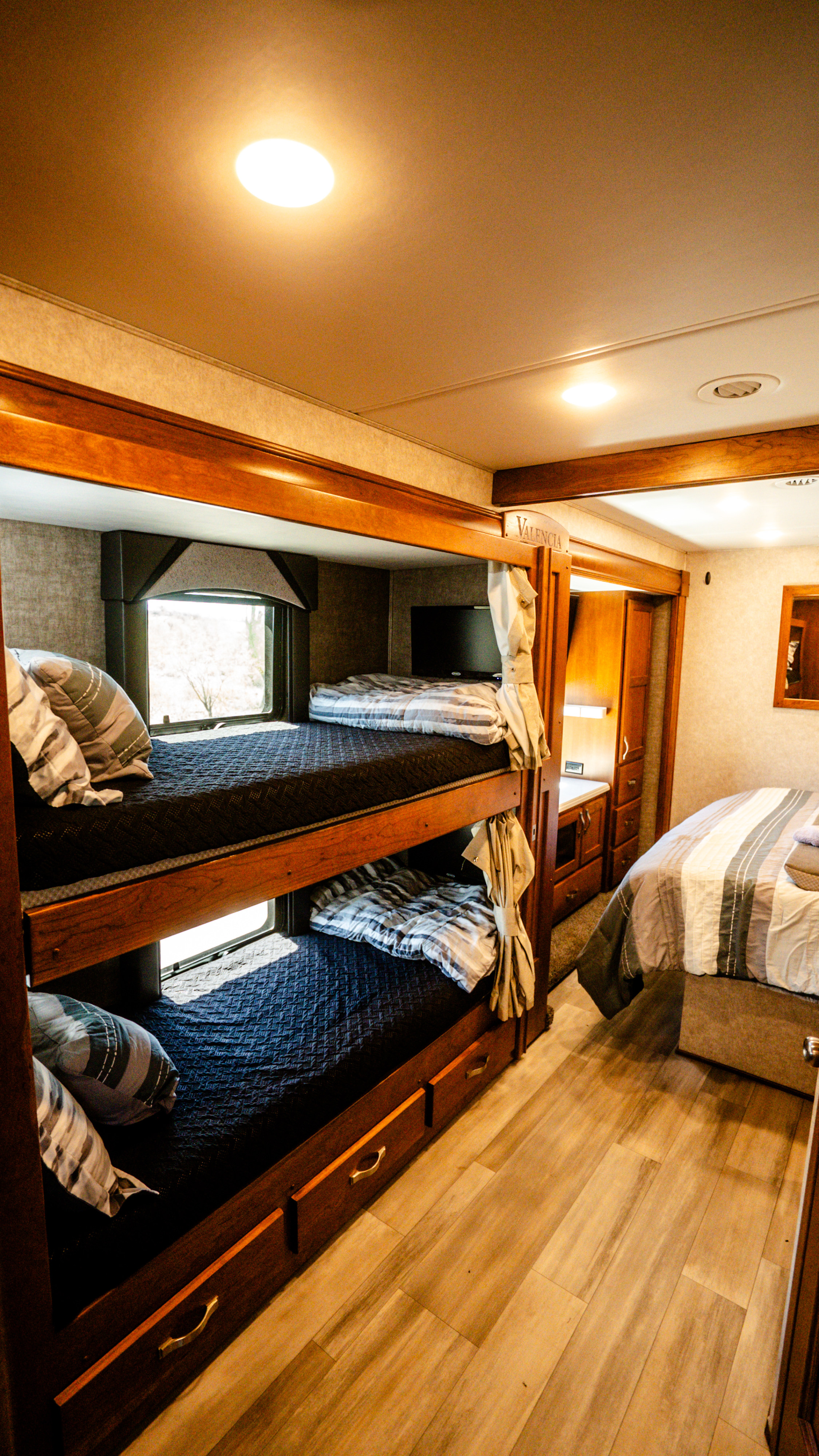 Spacious RV rental bedroom with cozy bunk beds and a main bed, featuring warm wooden accents and ample sleeping space.. Renegade Custom Coaches Valencia 2022