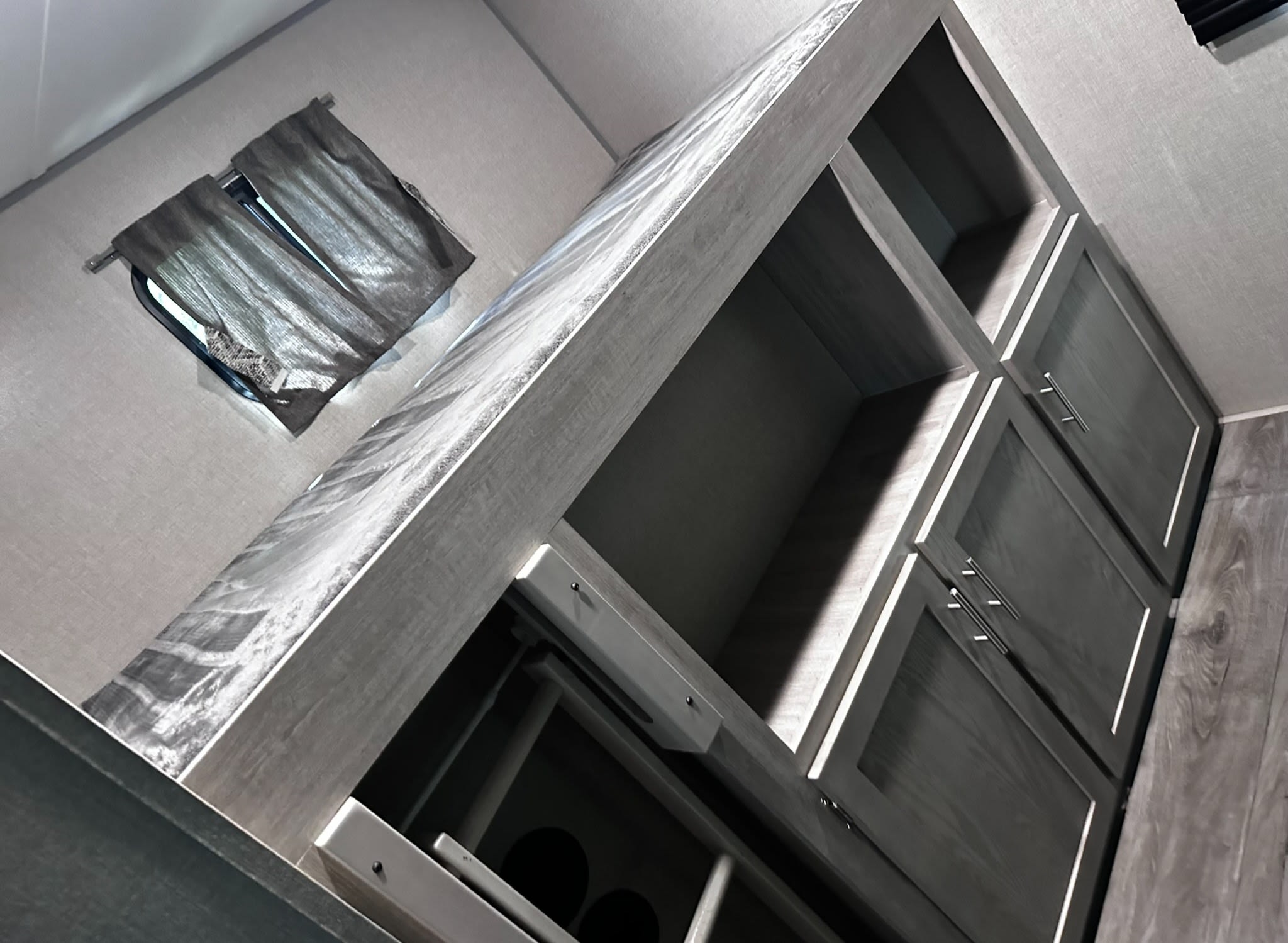 RV rental interior featuring a window with curtains, grey modular shelving, cabinets, and a covered sleeping area.. Coachmen catalina 2023