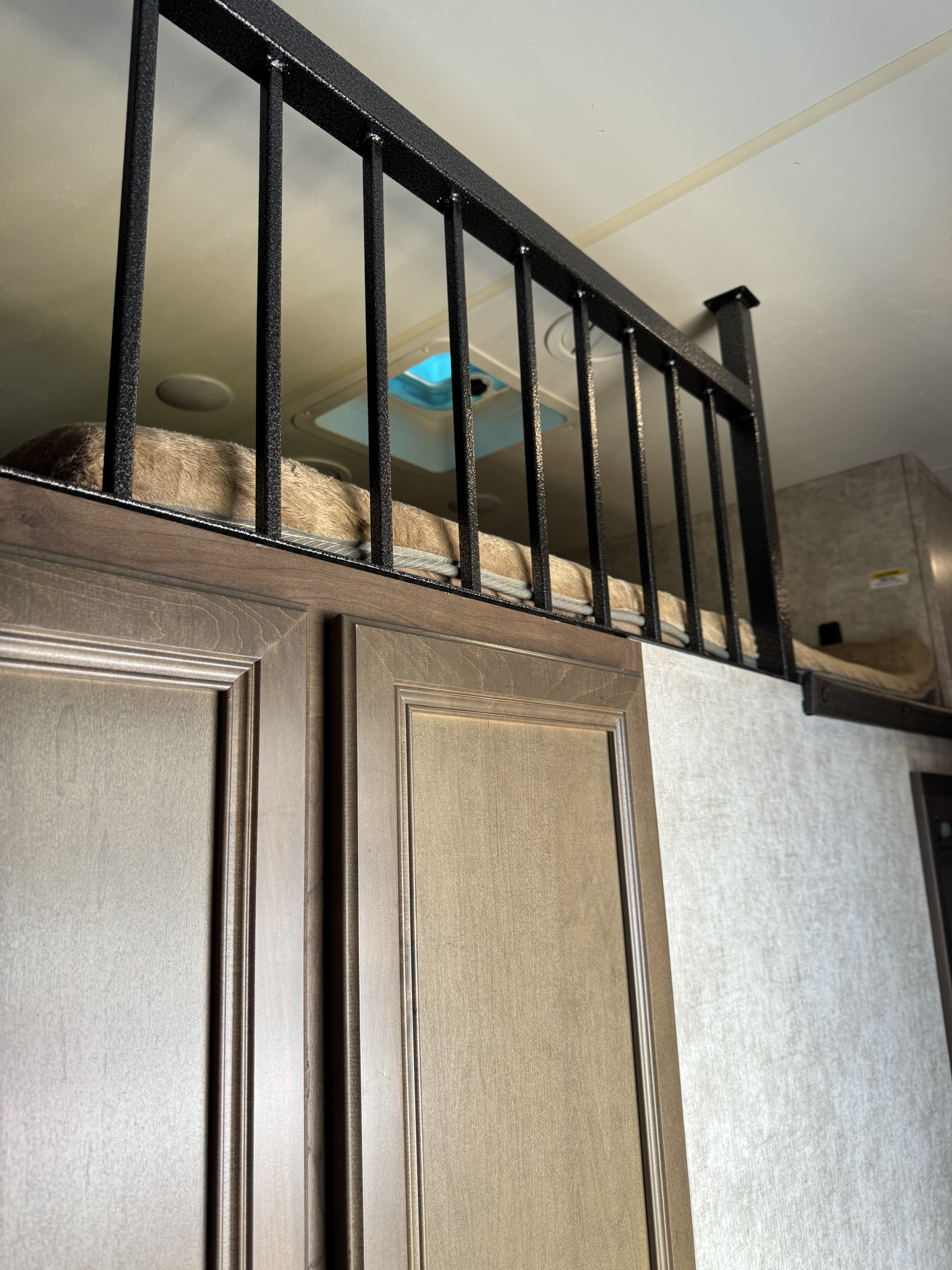 RV rental interior: A fluffy loft bed seen above wooden cabinets, framed by a black metal railing and a ceiling skylight.. Highland Ridge RV Open Range 2018