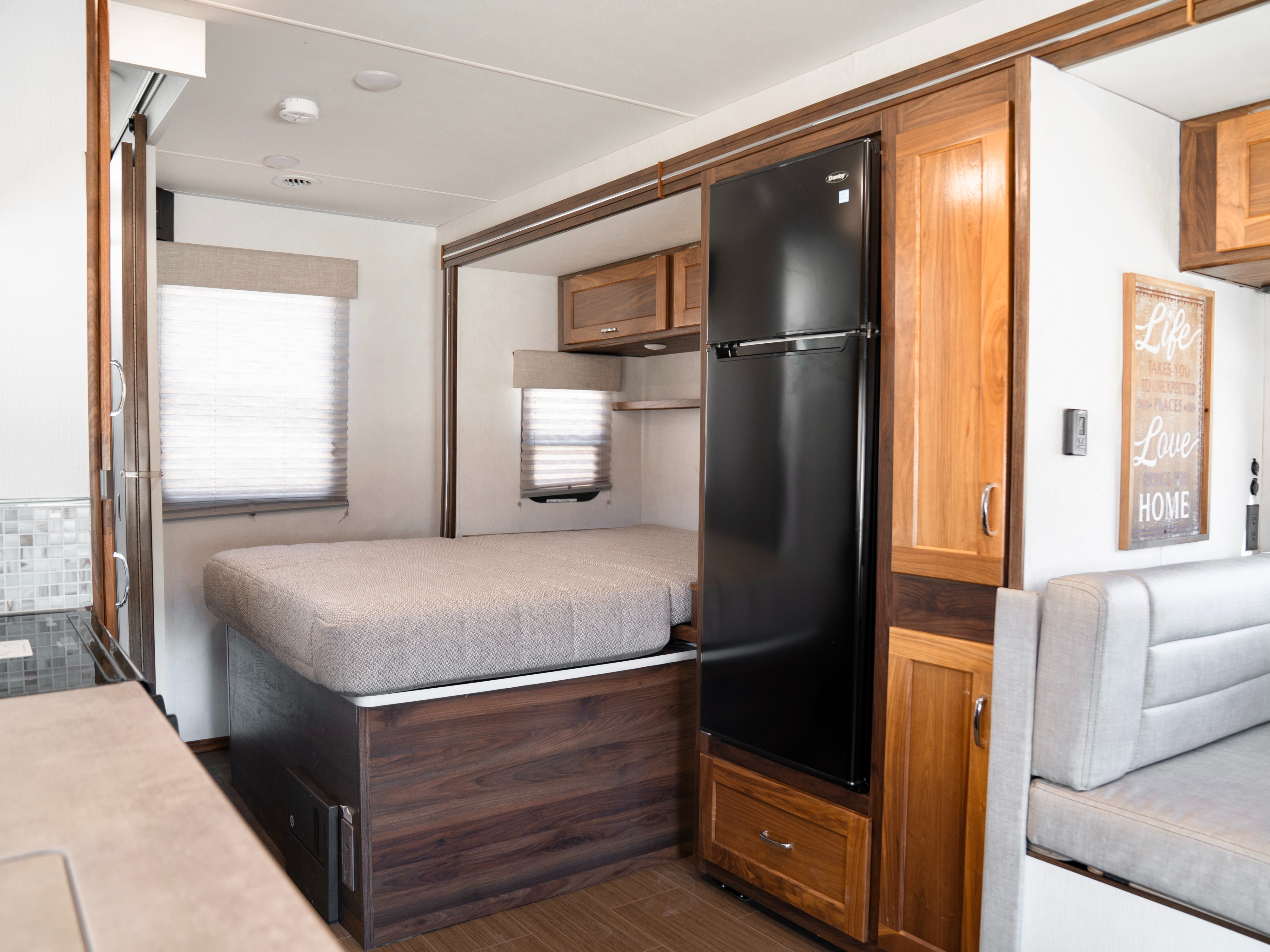 RV rental interior: A compact living area with a bed in a slide-out, refrigerator, and cabinets for efficient space.. Winnebago Vita 2020