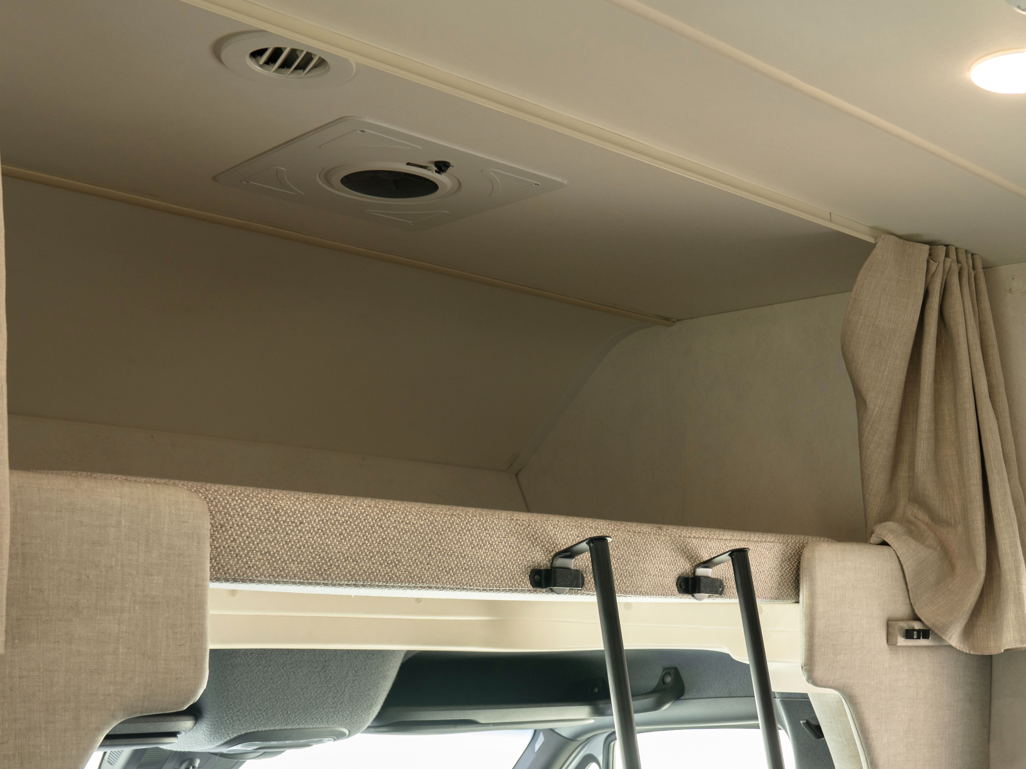 RV rental interior with a neutral-toned overhead bunk, ladder mounts, ceiling vents, and a privacy curtain.. Winnebago Vita 2020