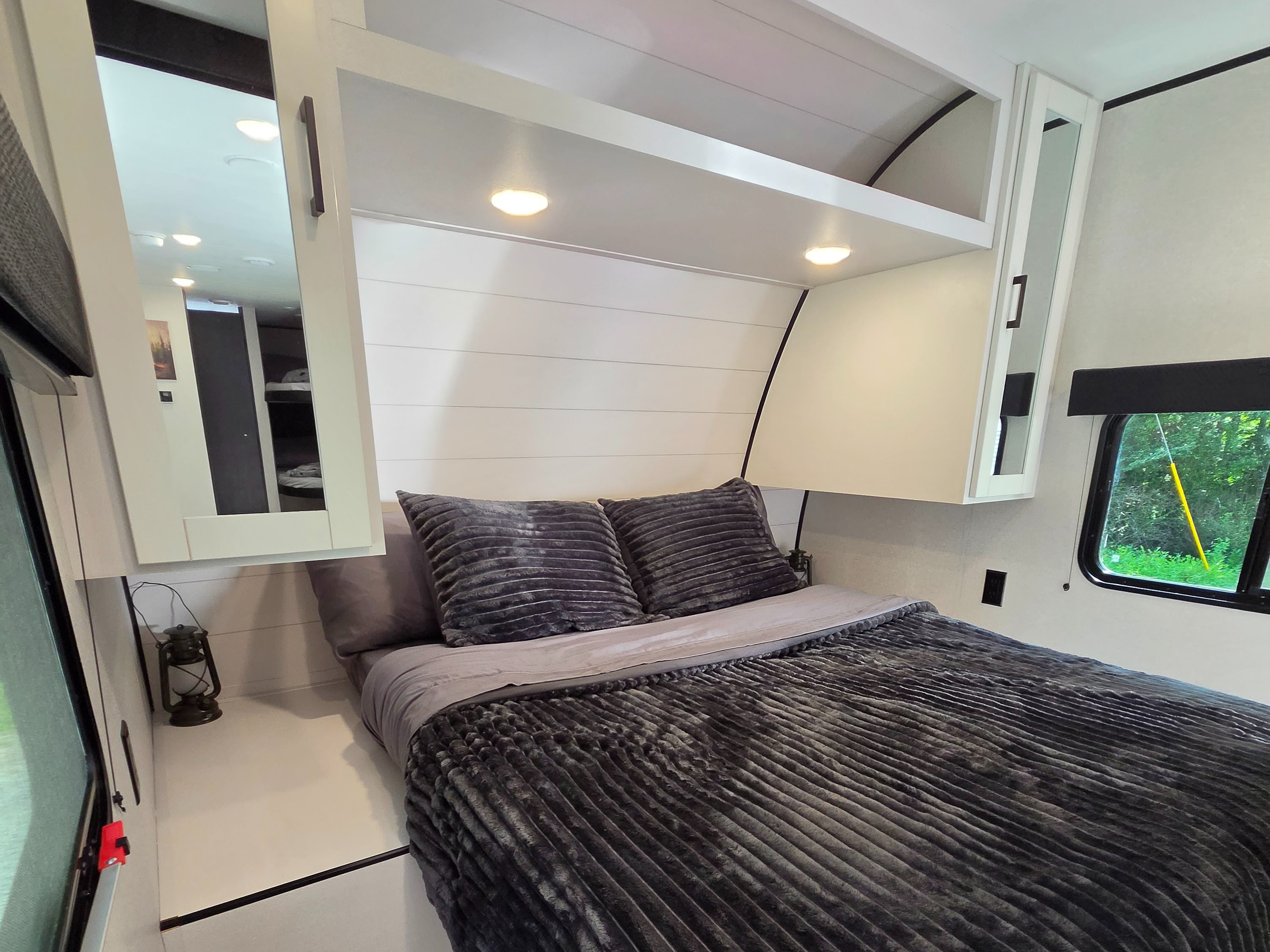 Explore this cozy RV rental bedroom interior, featuring a modern bed with dark grey bedding, overhead storage, and ambient lighting.. Jayco Jay Flight SLX 2026