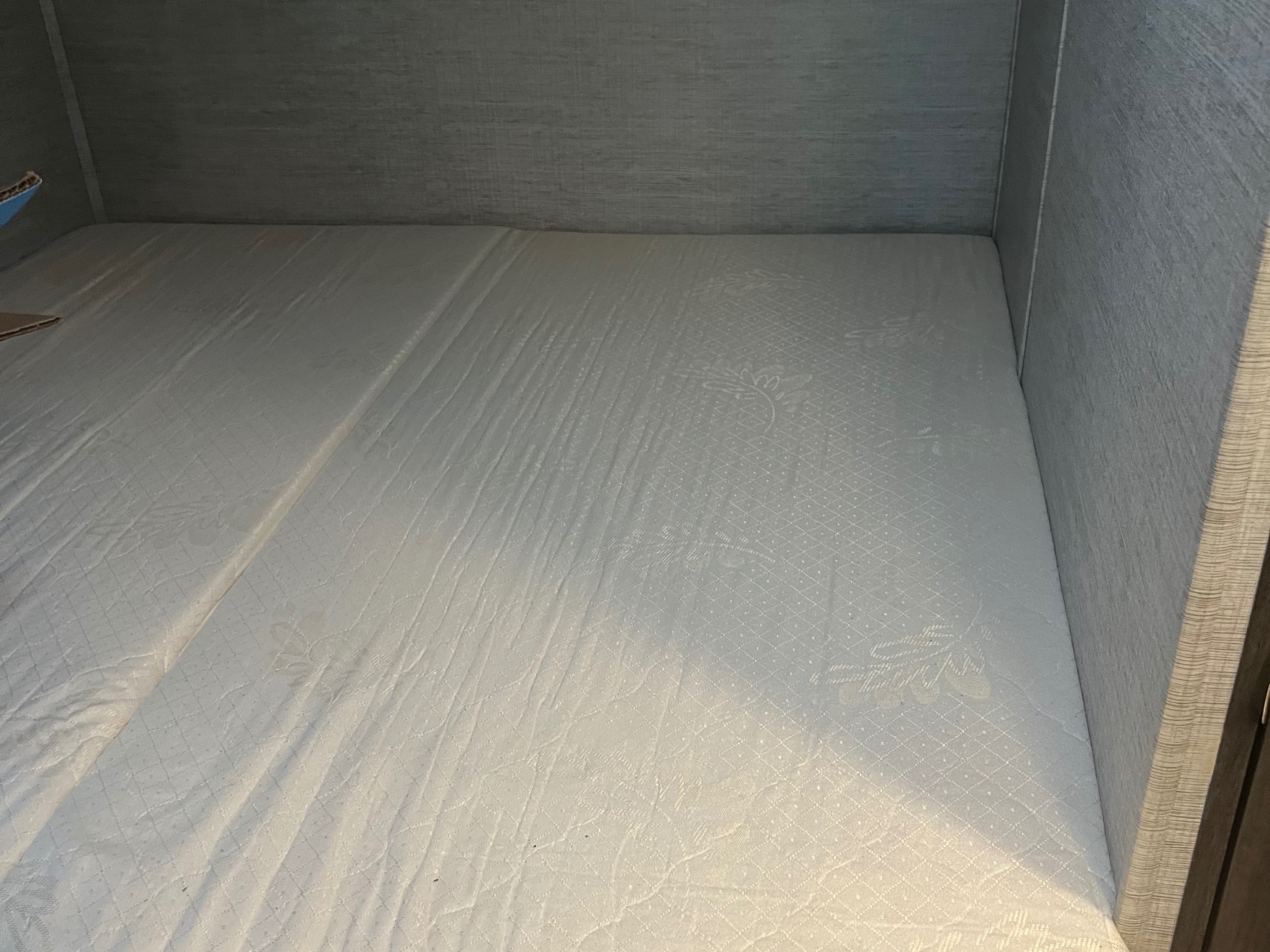This RV rental bed features a white quilted mattress in a compact sleeping nook, ready for your next adventure.. Jayco Redhawk SE 2023